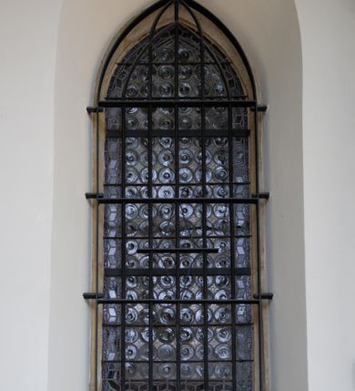 Zdjęcie nr 12: Kościół orientowany, jest budowlą murowaną z kamienia, na rzucie podłużnym. Korpus jednonawowy i dwuprzęsłowy. Do stosunkowo szerokiego, jednoprzęsłowego, zamkniętego trójbocznie prezbiterium od północy przylega zakrystia, a na osi kościoła, od zachodu kruchta. Prezbiterium przekryte jest sklepieniem krzyżowo-żebrowym, a nawa drewnianym sklepieniem kolebkowymi.  Przestrzeń prezbiterium od korpusu nawowego oddziela ostrołukowa arkada tęczowa i drewniana balustrada. Artykulację ścian na zewnątrz kościoła stanowi wieniec przypór ujmujących ściany i naroża korpusu nawowego i prezbiterium.  Do wnętrza prowadzą trzy otwory drzwiowe – jeden przez kruchtę w elewacji północnej, jeden w północnej ścianie korpusu nawowego i jeden przez zakrystię. Dwuskrzydłowe drzwi w kruchcie ujęte są portalem zamkniętym łukiem dwuramiennym, portale pozostałych otworów drzwiowych są ostrołukowe. Ściany korpusu nawowego i prezbiterium przeprute są smukłymi, ostrołukowymi oknami, w nawie wypełnionymi gomółkami, a w prezbiterium dekoracją maswerkową. W szczycie fasady para małych, wąskich okienek w kształcie stojących prostokątów, analogiczne w szczycie kruchty. Korpus nawowy, prezbiterium i zakrystia przekryte są jednym dachem dwuspadowym, wykonanym z blachy, kruchta także dachem dwuspadowym. Na połączeniu nawy i prezbiterium umieszczona jest wieżyczka na sygnaturkę, także obita blachą. Kolorystyka tynków kościoła utrzymana jest w kolorze białym, fasada i kruchta są kamienne. 