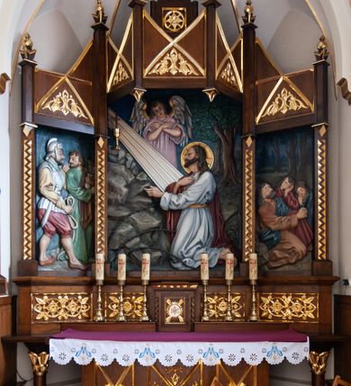 Zdjęcie nr 12: Kościół jest położony w centrum wsi, na północ od główne drogi we wsi, na placu otoczonym kamiennym murem, nakrytym betonowym daszkiem, obsadzony ozdobnym drzewostanem. Wejście na plac kościelny prowadzi przez bramę od południa i wąską furtkę od zachodu. Kościół jest budowlą założoną na planie krzyża łacińskiego, murowaną, skierowaną na północ, trójnawową z transeptem i prezbiterium zakończonym wielobocznie. Wewnątrz dwuprzęsłowe nawy oddzielone są ostrołukowymi arkadami wspartymi na zdwojonych filarach oraz na parze kolumn pośrodku świątyni. Podpory wspierają sklepienie krzyżowo-żebrowe. Od fasady dostawiona masywna wieża na planie prostokąta, zwężająca się ku górze, nakryta namiotowym daszkiem i zwieńczona krzyżem. Wejście południowe w formie prostokątnego portalu, ujętego w dużą ostrołukową arkadę wykonaną z kamiennej okładziny. Powyżej na tle trójdzielnego okna ustawiona jest figura Chrystusa. Pomiędzy zachodnim ramieniem transeptu, a prezbiterium dostawiona zakrystia z wejściem od północy, analogicznie po drugiej stronie kościoła kaplica Najświętszego Serca Pana Jezusa. Nad skrzyżowaniem ramion transeptu umieszczona jest ażurowa wieżyczka na sygnaturkę. Całość opięta szkarpami. Detale dekoracyjne, takie jak narożniki, portale, gzymsy i obramowania okien wykonane z piaskowca. Do świątyni prowadzi też zachodni przedsionek.