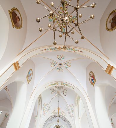 Zdjęcie nr 3: Kościół jest położony w centrum wsi, na północ od główne drogi we wsi, na placu otoczonym kamiennym murem, nakrytym betonowym daszkiem, obsadzony ozdobnym drzewostanem. Wejście na plac kościelny prowadzi przez bramę od południa i wąską furtkę od zachodu. Kościół jest budowlą założoną na planie krzyża łacińskiego, murowaną, skierowaną na północ, trójnawową z transeptem i prezbiterium zakończonym wielobocznie. Wewnątrz dwuprzęsłowe nawy oddzielone są ostrołukowymi arkadami wspartymi na zdwojonych filarach oraz na parze kolumn pośrodku świątyni. Podpory wspierają sklepienie krzyżowo-żebrowe. Od fasady dostawiona masywna wieża na planie prostokąta, zwężająca się ku górze, nakryta namiotowym daszkiem i zwieńczona krzyżem. Wejście południowe w formie prostokątnego portalu, ujętego w dużą ostrołukową arkadę wykonaną z kamiennej okładziny. Powyżej na tle trójdzielnego okna ustawiona jest figura Chrystusa. Pomiędzy zachodnim ramieniem transeptu, a prezbiterium dostawiona zakrystia z wejściem od północy, analogicznie po drugiej stronie kościoła kaplica Najświętszego Serca Pana Jezusa. Nad skrzyżowaniem ramion transeptu umieszczona jest ażurowa wieżyczka na sygnaturkę. Całość opięta szkarpami. Detale dekoracyjne, takie jak narożniki, portale, gzymsy i obramowania okien wykonane z piaskowca. Do świątyni prowadzi też zachodni przedsionek.