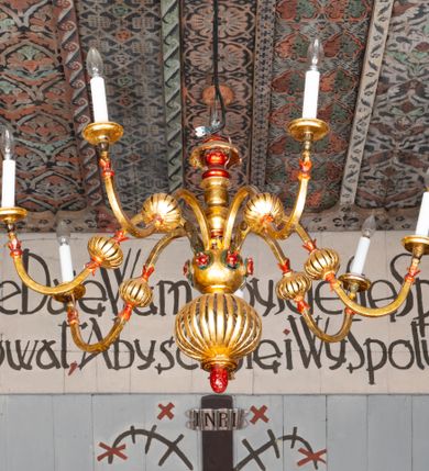 Zdjęcie nr 28: Kościół drewniany, orientowany, składający się z babińca, nawy głównej z przylegającą do niej od północy kaplicą boczną i kruchtą od południa oraz prezbiterium z zakrystią od północy. Prezbiterium i nawa w konstrukcji zrębowej, wieża, soboty i kruchta w słupowej. Kościół jednonawowy, nawa prawie kwadratowa, prezbiterium prostokątne, zamknięte prosto, oddzielone ścianą tęczową. Otwór tęczowy zamknięty łukiem dwuramiennym z biegnącą w poprzek grubą belką. Ściany gładkie, pokryte dekoracją malarską imitującą poziomo ułożone belki z uszczelniającymi je kiczkami, scenami figuralnymi, zacheuszkami i pasami ornamentalnymi. W nawie od zachodu chór muzyczny wsparty na dwóch, profilowanych słupach, z parapetem wybrzuszonym pośrodku; z dekoracją malarską o motywach geometryczno-roślinnych. Nawa i prezbiterium naryte pozornym sklepieniem z pułapami lekko zaokrąglonymi po bokach. Na całości przekrycia dekoracja malarska. W prezbiterium są to postacie aniołów wśród stylizowanych kwiatów na stropie adorujących monogram maryjny, nawę dekorują motywy roślinne. Anioły zdobią również sklepienie kaplicy. Strop babińca oraz fragmenty prezbiterium pokrywa oryginalna dekoracja patronowa złożona z motywów geometrycznych oraz figuralnych. W nawie głównej trzy okna, w prezbiterium i babińcu po dwa – od południa, kolejne do zakrystii; zamknięte łukiem dwuspadowym. Główne wejście od zachodu, drugie przez kruchtę od południa, trzecie do zakrystii. Portal południowy ostrołukowy, dekorowany ornamentem sznurowym, portal do zakrystii zamknięty łukiem w ośli grzbiet. Od zachodu kwadratowa wieża o pochyłych ścianach, z nadwieszoną izbicą, zwieńczona czteropołaciowym, ostrosłupowym hełmem gontowym. Izbica wieży oszalowana dookoła deskami zakończonymi u dołu ozdobnie wyrzynaną koronką. Od południa i wschodu soboty, czyli rodzaj podcieni,  w pozostałych miejscach gontowy kołnierz. Ściany świątyni oraz kaplicy są od zewnątrz szalowane deskami, wieża oraz przedsionek obite są gontem. Dachy i zadaszenia sobot pokryte gontem, kopuła kaplicy oraz wieżyczka na sygnaturkę pokryta blachą. 