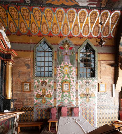 Zdjęcie nr 13: Kościół drewniany, orientowany, składający się z babińca, nawy głównej z przylegającą do niej od północy kaplicą boczną i kruchtą od południa oraz prezbiterium z zakrystią od północy. Prezbiterium i nawa w konstrukcji zrębowej, wieża, soboty i kruchta w słupowej. Kościół jednonawowy, nawa prawie kwadratowa, prezbiterium prostokątne, zamknięte prosto, oddzielone ścianą tęczową. Otwór tęczowy zamknięty łukiem dwuramiennym z biegnącą w poprzek grubą belką. Ściany gładkie, pokryte dekoracją malarską imitującą poziomo ułożone belki z uszczelniającymi je kiczkami, scenami figuralnymi, zacheuszkami i pasami ornamentalnymi. W nawie od zachodu chór muzyczny wsparty na dwóch, profilowanych słupach, z parapetem wybrzuszonym pośrodku; z dekoracją malarską o motywach geometryczno-roślinnych. Nawa i prezbiterium naryte pozornym sklepieniem z pułapami lekko zaokrąglonymi po bokach. Na całości przekrycia dekoracja malarska. W prezbiterium są to postacie aniołów wśród stylizowanych kwiatów na stropie adorujących monogram maryjny, nawę dekorują motywy roślinne. Anioły zdobią również sklepienie kaplicy. Strop babińca oraz fragmenty prezbiterium pokrywa oryginalna dekoracja patronowa złożona z motywów geometrycznych oraz figuralnych. W nawie głównej trzy okna, w prezbiterium i babińcu po dwa – od południa, kolejne do zakrystii; zamknięte łukiem dwuspadowym. Główne wejście od zachodu, drugie przez kruchtę od południa, trzecie do zakrystii. Portal południowy ostrołukowy, dekorowany ornamentem sznurowym, portal do zakrystii zamknięty łukiem w ośli grzbiet. Od zachodu kwadratowa wieża o pochyłych ścianach, z nadwieszoną izbicą, zwieńczona czteropołaciowym, ostrosłupowym hełmem gontowym. Izbica wieży oszalowana dookoła deskami zakończonymi u dołu ozdobnie wyrzynaną koronką. Od południa i wschodu soboty, czyli rodzaj podcieni,  w pozostałych miejscach gontowy kołnierz. Ściany świątyni oraz kaplicy są od zewnątrz szalowane deskami, wieża oraz przedsionek obite są gontem. Dachy i zadaszenia sobot pokryte gontem, kopuła kaplicy oraz wieżyczka na sygnaturkę pokryta blachą. 