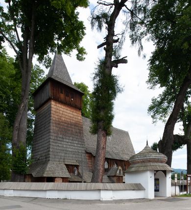 Zdjęcie nr 43: Kościół drewniany, orientowany, składający się z babińca, nawy głównej z przylegającą do niej od północy kaplicą boczną i kruchtą od południa oraz prezbiterium z zakrystią od północy. Prezbiterium i nawa w konstrukcji zrębowej, wieża, soboty i kruchta w słupowej. Kościół jednonawowy, nawa prawie kwadratowa, prezbiterium prostokątne, zamknięte prosto, oddzielone ścianą tęczową. Otwór tęczowy zamknięty łukiem dwuramiennym z biegnącą w poprzek grubą belką. Ściany gładkie, pokryte dekoracją malarską imitującą poziomo ułożone belki z uszczelniającymi je kiczkami, scenami figuralnymi, zacheuszkami i pasami ornamentalnymi. W nawie od zachodu chór muzyczny wsparty na dwóch, profilowanych słupach, z parapetem wybrzuszonym pośrodku; z dekoracją malarską o motywach geometryczno-roślinnych. Nawa i prezbiterium naryte pozornym sklepieniem z pułapami lekko zaokrąglonymi po bokach. Na całości przekrycia dekoracja malarska. W prezbiterium są to postacie aniołów wśród stylizowanych kwiatów na stropie adorujących monogram maryjny, nawę dekorują motywy roślinne. Anioły zdobią również sklepienie kaplicy. Strop babińca oraz fragmenty prezbiterium pokrywa oryginalna dekoracja patronowa złożona z motywów geometrycznych oraz figuralnych. W nawie głównej trzy okna, w prezbiterium i babińcu po dwa – od południa, kolejne do zakrystii; zamknięte łukiem dwuspadowym. Główne wejście od zachodu, drugie przez kruchtę od południa, trzecie do zakrystii. Portal południowy ostrołukowy, dekorowany ornamentem sznurowym, portal do zakrystii zamknięty łukiem w ośli grzbiet. Od zachodu kwadratowa wieża o pochyłych ścianach, z nadwieszoną izbicą, zwieńczona czteropołaciowym, ostrosłupowym hełmem gontowym. Izbica wieży oszalowana dookoła deskami zakończonymi u dołu ozdobnie wyrzynaną koronką. Od południa i wschodu soboty, czyli rodzaj podcieni,  w pozostałych miejscach gontowy kołnierz. Ściany świątyni oraz kaplicy są od zewnątrz szalowane deskami, wieża oraz przedsionek obite są gontem. Dachy i zadaszenia sobot pokryte gontem, kopuła kaplicy oraz wieżyczka na sygnaturkę pokryta blachą. 