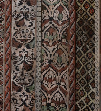 Zdjęcie nr 31: Kościół drewniany, orientowany, składający się z babińca, nawy głównej z przylegającą do niej od północy kaplicą boczną i kruchtą od południa oraz prezbiterium z zakrystią od północy. Prezbiterium i nawa w konstrukcji zrębowej, wieża, soboty i kruchta w słupowej. Kościół jednonawowy, nawa prawie kwadratowa, prezbiterium prostokątne, zamknięte prosto, oddzielone ścianą tęczową. Otwór tęczowy zamknięty łukiem dwuramiennym z biegnącą w poprzek grubą belką. Ściany gładkie, pokryte dekoracją malarską imitującą poziomo ułożone belki z uszczelniającymi je kiczkami, scenami figuralnymi, zacheuszkami i pasami ornamentalnymi. W nawie od zachodu chór muzyczny wsparty na dwóch, profilowanych słupach, z parapetem wybrzuszonym pośrodku; z dekoracją malarską o motywach geometryczno-roślinnych. Nawa i prezbiterium naryte pozornym sklepieniem z pułapami lekko zaokrąglonymi po bokach. Na całości przekrycia dekoracja malarska. W prezbiterium są to postacie aniołów wśród stylizowanych kwiatów na stropie adorujących monogram maryjny, nawę dekorują motywy roślinne. Anioły zdobią również sklepienie kaplicy. Strop babińca oraz fragmenty prezbiterium pokrywa oryginalna dekoracja patronowa złożona z motywów geometrycznych oraz figuralnych. W nawie głównej trzy okna, w prezbiterium i babińcu po dwa – od południa, kolejne do zakrystii; zamknięte łukiem dwuspadowym. Główne wejście od zachodu, drugie przez kruchtę od południa, trzecie do zakrystii. Portal południowy ostrołukowy, dekorowany ornamentem sznurowym, portal do zakrystii zamknięty łukiem w ośli grzbiet. Od zachodu kwadratowa wieża o pochyłych ścianach, z nadwieszoną izbicą, zwieńczona czteropołaciowym, ostrosłupowym hełmem gontowym. Izbica wieży oszalowana dookoła deskami zakończonymi u dołu ozdobnie wyrzynaną koronką. Od południa i wschodu soboty, czyli rodzaj podcieni,  w pozostałych miejscach gontowy kołnierz. Ściany świątyni oraz kaplicy są od zewnątrz szalowane deskami, wieża oraz przedsionek obite są gontem. Dachy i zadaszenia sobot pokryte gontem, kopuła kaplicy oraz wieżyczka na sygnaturkę pokryta blachą. 