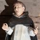 Zdjęcie nr 1: Figura drążona ustawiona na niewielkim, prostopadłościennym postumencie. Święty ukazany całopostaciowo, frontalnie z sylwetką wygiętą w kształt litery „S”, z rękoma lekko zgiętymi w łokciach i uniesionymi do góry. Twarz owalna z wyraźnie zaakcentowanymi kośćmi policzkowymi, karnacja jasna. Oczy szeroko otwarte, wpatrzone przed siebie, usta lekko rozchylone.
Włosy koloru brązowego. Na głowie widoczna tonsura. Święty ubrany jest w biały habit dominikański ze szkaplerzem oraz czarny płaszcz z kapturem. Spod habitu widoczne są brązowe buty. Szaty podkreślające anatomię. Figura w pełni polichromowana.