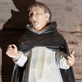 Zdjęcie nr 1: Figura drążona ustawiona na niewielkim, prostopadłościennym postumencie. Święty ukazany całopostaciowo, frontalnie z sylwetką wygiętą w kształt litery „S”, z rękoma lekko zgiętymi w łokciach i uniesionymi do góry. Twarz owalna z wyraźnie zaakcentowanymi kośćmi policzkowymi, karnacja jasna. Oczy szeroko otwarte, wpatrzone przed siebie, usta lekko rozchylone.
Włosy koloru brązowego. Na głowie widoczna tonsura. Święty ubrany jest w biały habit dominikański ze szkaplerzem oraz czarny płaszcz z kapturem. Spod habitu widoczne są brązowe buty. Szaty podkreślające anatomię. Figura w pełni polichromowana.