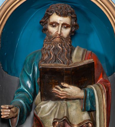 Zdjęcie nr 1: Rzeźba pełnoplastyczna, przyścienna. Święty Paweł ukazany został w całej postaci, frontalnie, w pozycji stojącej, z lewą nogą wspartą na skale. W lewej dłoni trzyma otwartą księgę, zaś w prawej niegdyś znajdował się miecz. Głowa świętego jest lekko pochylona w lewą stronę, a wzrok opuszczony na karty księgi. Ubrany jest w niebieską szatę z długimi rękawami, spływającą do stóp. Szata dekorowana jest złotą lamówką. Na ramiona św. Paweł narzucony ma czerwony płaszcz, z jasnym podbiciem. Wierzchnie odzienie dekorowane jest złotą lamówką i złotym ornamentem roślinnym w formie pasa biegnącego wzdłuż jego krawędzi. Poła płaszcza przerzucona jest przez lewe ramię świętego, spływa z lewego przedramienia i podtrzymywana jest na wysokości brzucha, gdzie odwija się ukazując podszewkę. Postać ma wyraziste rysy twarzy, długi, wąski nos, lekko pofalowane, brązowe włosy przykrywające uszy, oraz brązowe wąsy i długą brodę.