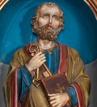 Zdjęcie nr 1: Rzeźba pełnoplastyczna, przyścienna, drążona od tyłu, przedstawia Świętego Piotra w całej postaci. Postać została ujęta frontalnie, umieszczona na niskiej wielobocznej podstawie. Święty stoi z prawą nogą zgiętą w kolanie. Lewa dłonią przytrzymuje zamkniętą księgę, którą opiera o brzuch, w prawej dłoni, na wysokości klatki piersiowej, trzyma dwa klucze. Ubrany jest w długą szatę koloru niebieskiego, ze złotą lamówką, z długimi rękawami. Na ramiona zarzucony ma zielony płaszcz z czerwoną podszewką. Płaszcz dekorowany jest ornamentem roślinnym, który biegnie wzdłuż krawędzi tkaniny. Głowę lekko przechyla w lewą stronę, wzrok skierowany ma ku górze. Jasne falowane włosy zakrywają uszy. Twarz okalają wąsy oraz krótka broda.