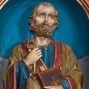 Zdjęcie nr 1: Rzeźba pełnoplastyczna, przyścienna, drążona od tyłu, przedstawia Świętego Piotra w całej postaci. Postać została ujęta frontalnie, umieszczona na niskiej wielobocznej podstawie. Święty stoi z prawą nogą zgiętą w kolanie. Lewa dłonią przytrzymuje zamkniętą księgę, którą opiera o brzuch, w prawej dłoni, na wysokości klatki piersiowej, trzyma dwa klucze. Ubrany jest w długą szatę koloru niebieskiego, ze złotą lamówką, z długimi rękawami. Na ramiona zarzucony ma zielony płaszcz z czerwoną podszewką. Płaszcz dekorowany jest ornamentem roślinnym, który biegnie wzdłuż krawędzi tkaniny. Głowę lekko przechyla w lewą stronę, wzrok skierowany ma ku górze. Jasne falowane włosy zakrywają uszy. Twarz okalają wąsy oraz krótka broda.