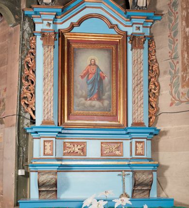 Zdjęcie nr 1: Nastawa ołtarzowa architektoniczna, jednoosiowa, jednokondygnacyjna. Ołtarz drewniany, sarkofagowy, w formie odwróconego trapezu. Mensa drewniana, silnie wysunięta. Antependium w formie odwróconego trapezu, na cokole, w polu romb ujęty ramą z rozetą. Ołtarz flankują romby ujęte ramą.
Retabulum na dwustrefowym cokole, zryzalitowanym na skraju; w konsole dolnej strefy dźwigaja cokoły górnej. Ryzality podtrzymują parę półfilarów o stylizowanych kapitelach kompozytowych i kanelowanych trzonach. Podpory dźwigają pełne belkowanie, wyłamane na ich osi, z silnie wysuniętym, bogato profilowanym gzymsem; nad polem środkowym niepełne, przyjmujące kształt trzech boków z ośmioboku; Na gzymsie, na osi podpór figury dwóch karmelitańskich świętych. W polu środkowym nisza w formie stojącego prostokąta zamkniętego łukiem nadwieszonym z uskokiem, ujęta profilowaną ramą; wewnątrz profilowana rama w formie stojącego prostokąta, w której znajduje się obraz Najświętsze Serce Jezusa w ramie. Na belkowaniu, nad polem środkowym medalion z monogramem IHS w glorii promienistej, którego podstawę stanowi fragment rocaille.
W górnej strefie cokołu dwie płyciny w formie leżącego prostokąta z rozetami; cokoły kolumn zrobione z trzech stron płycinami z malowaną dekoracją roślinną. W partii fryzu na osi podpór rozety. Rama niszy zwieńczona elementem rocaille. Retabulum ujęte uszami utworzonymi z suchego akantu.
Struktura polichromowana w kolorze jasnoniebieskim, profile na niebiesko; konsole i trzony marmoryzowane; ornamentyka, ramy, profile i gloria złocone.
