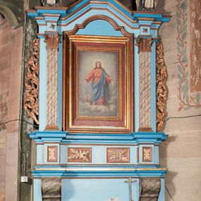 Zdjęcie nr 1: Nastawa ołtarzowa architektoniczna, jednoosiowa, jednokondygnacyjna. Ołtarz drewniany, sarkofagowy, w formie odwróconego trapezu. Mensa drewniana, silnie wysunięta. Antependium w formie odwróconego trapezu, na cokole, w polu romb ujęty ramą z rozetą. Ołtarz flankują romby ujęte ramą.
Retabulum na dwustrefowym cokole, zryzalitowanym na skraju; w konsole dolnej strefy dźwigaja cokoły górnej. Ryzality podtrzymują parę półfilarów o stylizowanych kapitelach kompozytowych i kanelowanych trzonach. Podpory dźwigają pełne belkowanie, wyłamane na ich osi, z silnie wysuniętym, bogato profilowanym gzymsem; nad polem środkowym niepełne, przyjmujące kształt trzech boków z ośmioboku; Na gzymsie, na osi podpór figury dwóch karmelitańskich świętych. W polu środkowym nisza w formie stojącego prostokąta zamkniętego łukiem nadwieszonym z uskokiem, ujęta profilowaną ramą; wewnątrz profilowana rama w formie stojącego prostokąta, w której znajduje się obraz Najświętsze Serce Jezusa w ramie. Na belkowaniu, nad polem środkowym medalion z monogramem IHS w glorii promienistej, którego podstawę stanowi fragment rocaille.
W górnej strefie cokołu dwie płyciny w formie leżącego prostokąta z rozetami; cokoły kolumn zrobione z trzech stron płycinami z malowaną dekoracją roślinną. W partii fryzu na osi podpór rozety. Rama niszy zwieńczona elementem rocaille. Retabulum ujęte uszami utworzonymi z suchego akantu.
Struktura polichromowana w kolorze jasnoniebieskim, profile na niebiesko; konsole i trzony marmoryzowane; ornamentyka, ramy, profile i gloria złocone.
