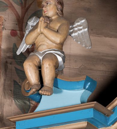 Zdjęcie nr 3: Nastawa ołtarzowa architektoniczna, jednoosiowa, jednokondygnacyjna, ze zwieńczeniem. Ołtarz drewniany, sarkofagowy, zwężający się ku dołowi, na cokole. Mensa drewniana, silnie wysunięta.  Antependium w kształcie trapezu, w polu romb ujęty obramieniem, z rozetą, flankowany dwoma rombami. Retabulum na dwustrefowym cokole, flankowane para półfilarów o stylizowanych kapitelach kompozytowych i kanelowanych trzonach, umieszczonych na cokołach nadwieszonych na konsolach. Podpory dźwigają pełne belkowanie, występujące na ich osi, z silnie wysuniętym, bogato profilowanym gzymsem, nad polem środkowym wyłamanym trójbocznie. W zwieńczeniu w osiach podpór odcinki przerwanego przyczółka, na których siedzą dwa uskrzydlone putta. W polu środkowym nisza w kształcie stojącego prostokąta zamkniętego łukiem nadwieszonym z uskokiem, ujęta profilowaną ramą; wewnątrz profilowana rama w kształcie stojącego prostokąta, w której znajduje się obraz Matki Boskiej z Dzieciątkiem w ramie dekorowanej płaskorzeźbionymi motywami liści akantu. W zwieńczeniu, nad polem środkowym medalion z ze splecionymi literami imienia Marya w glorii promienistej, u dołu motyw rocaille’u. W górnej strefie cokołu dwie płyciny w formie leżącego prostokąta z rozetami; cokoły kolumn zdobione z trzech stron płycinami z malowaną dekoracją roślinną. W partii fryzu na osi podpór rozety. Rama niszy zwieńczona motywem rocaille’u. Retabulum ujęte uszami utworzonymi z motywów stylizowanych liści akantu i elementów małżowiny. Struktura polichromowana w kolorze jasnoniebieskim, profile na niebiesko; konsole i trzony marmoryzowane; ornamentyka, ramy, profile i gloria złocone.