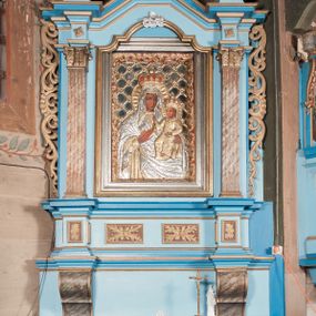 Zdjęcie nr 1: Nastawa ołtarzowa architektoniczna, jednoosiowa, jednokondygnacyjna, ze zwieńczeniem. Ołtarz drewniany, sarkofagowy, zwężający się ku dołowi, na cokole. Mensa drewniana, silnie wysunięta.  Antependium w kształcie trapezu, w polu romb ujęty obramieniem, z rozetą, flankowany dwoma rombami. Retabulum na dwustrefowym cokole, flankowane para półfilarów o stylizowanych kapitelach kompozytowych i kanelowanych trzonach, umieszczonych na cokołach nadwieszonych na konsolach. Podpory dźwigają pełne belkowanie, występujące na ich osi, z silnie wysuniętym, bogato profilowanym gzymsem, nad polem środkowym wyłamanym trójbocznie. W zwieńczeniu w osiach podpór odcinki przerwanego przyczółka, na których siedzą dwa uskrzydlone putta. W polu środkowym nisza w kształcie stojącego prostokąta zamkniętego łukiem nadwieszonym z uskokiem, ujęta profilowaną ramą; wewnątrz profilowana rama w kształcie stojącego prostokąta, w której znajduje się obraz Matki Boskiej z Dzieciątkiem w ramie dekorowanej płaskorzeźbionymi motywami liści akantu. W zwieńczeniu, nad polem środkowym medalion z ze splecionymi literami imienia Marya w glorii promienistej, u dołu motyw rocaille’u. W górnej strefie cokołu dwie płyciny w formie leżącego prostokąta z rozetami; cokoły kolumn zdobione z trzech stron płycinami z malowaną dekoracją roślinną. W partii fryzu na osi podpór rozety. Rama niszy zwieńczona motywem rocaille’u. Retabulum ujęte uszami utworzonymi z motywów stylizowanych liści akantu i elementów małżowiny. Struktura polichromowana w kolorze jasnoniebieskim, profile na niebiesko; konsole i trzony marmoryzowane; ornamentyka, ramy, profile i gloria złocone.