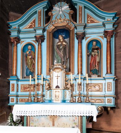 Zdjęcie nr 3: Retabulum ołtarzowe trójosiowe, na dwustrefowym cokole, jednokondygnacyjne, ze zwieńczeniem. Nastawa szersza od ołtarza, artykułowana jest kolumnami o gładkich trzonach i kompozytowych kapitelach, podtrzymującymi występujące się nad nią uproszczone belkowanie i gzyms. W polach pomiędzy kolumnami prostokątne nisze, pośrodku zamknięta uskokowo, w niej rzeźba patronki świątyni św. Marii Magdaleny; nisze w polach bocznych zamknięte półkoliście, w nich rzeźby św. Piotra i św. Pawła. W zwieńczeniu przerwany przyczółek zamknięty łukiem wklęsło-wypukłym, w osiach wewnętrznych kolumn wsparty na lizenach. W osi środkowej rzeźbiona Gołębica Ducha Świętego w glorii promienistej ujętej po bokach wolutami i od dołu motywami ornamentu małżowinowego. W części cokołowej w płycinach ujętych ramami umieszczono motywy ornamentu rocaille’owego. W przyczółku w płycinach motywy liści akantu. 
Na mensie tabernakulum połączone z Tronem Łaski do wystawienia monstrancji, na rzucie prostokąta, dwustrefowe, z dolną strefą ujętą wklęsłymi ściankami parawanowymi. W dolnej części tabernakulum znajdują się prostokątne drzwiczki z krzyżem i literami: IHS. Drzwiczki są ujęte kampanulami oraz ornamentem rocaille’owym. Tron wystawienia ujęto spływami wolutowymi w formie krzewu różanego, zakończonymi adorującymi uskrzydlonymi aniołami umieszczonymi na obłokach. Część środkowa tronu wystawienia jest obrotowa. Górną jego część zakończono łukiem wklęsło-wypukłym, i ozdobiono ornamentem kartuszowo-zawijanym oraz figurą leżącego baranka. Antependium prostokątne, malowane na płótnie, ujęte w drewniane ramy zdobione wicią roślinną. W centralnej części ukazany został krzyż na tle promieni, po bokach winna latorośl i kłosy zboża. 