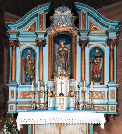 Zdjęcie nr 1: Retabulum ołtarzowe trójosiowe, na dwustrefowym cokole, jednokondygnacyjne, ze zwieńczeniem. Nastawa szersza od ołtarza, artykułowana jest kolumnami o gładkich trzonach i kompozytowych kapitelach, podtrzymującymi występujące się nad nią uproszczone belkowanie i gzyms. W polach pomiędzy kolumnami prostokątne nisze, pośrodku zamknięta uskokowo, w niej rzeźba patronki świątyni św. Marii Magdaleny; nisze w polach bocznych zamknięte półkoliście, w nich rzeźby św. Piotra i św. Pawła. W zwieńczeniu przerwany przyczółek zamknięty łukiem wklęsło-wypukłym, w osiach wewnętrznych kolumn wsparty na lizenach. W osi środkowej rzeźbiona Gołębica Ducha Świętego w glorii promienistej ujętej po bokach wolutami i od dołu motywami ornamentu małżowinowego. W części cokołowej w płycinach ujętych ramami umieszczono motywy ornamentu rocaille’owego. W przyczółku w płycinach motywy liści akantu. 
Na mensie tabernakulum połączone z Tronem Łaski do wystawienia monstrancji, na rzucie prostokąta, dwustrefowe, z dolną strefą ujętą wklęsłymi ściankami parawanowymi. W dolnej części tabernakulum znajdują się prostokątne drzwiczki z krzyżem i literami: IHS. Drzwiczki są ujęte kampanulami oraz ornamentem rocaille’owym. Tron wystawienia ujęto spływami wolutowymi w formie krzewu różanego, zakończonymi adorującymi uskrzydlonymi aniołami umieszczonymi na obłokach. Część środkowa tronu wystawienia jest obrotowa. Górną jego część zakończono łukiem wklęsło-wypukłym, i ozdobiono ornamentem kartuszowo-zawijanym oraz figurą leżącego baranka. Antependium prostokątne, malowane na płótnie, ujęte w drewniane ramy zdobione wicią roślinną. W centralnej części ukazany został krzyż na tle promieni, po bokach winna latorośl i kłosy zboża. 