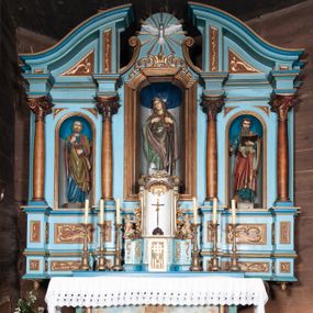 Zdjęcie nr 1: Retabulum ołtarzowe trójosiowe, na dwustrefowym cokole, jednokondygnacyjne, ze zwieńczeniem. Nastawa szersza od ołtarza, artykułowana jest kolumnami o gładkich trzonach i kompozytowych kapitelach, podtrzymującymi występujące się nad nią uproszczone belkowanie i gzyms. W polach pomiędzy kolumnami prostokątne nisze, pośrodku zamknięta uskokowo, w niej rzeźba patronki świątyni św. Marii Magdaleny; nisze w polach bocznych zamknięte półkoliście, w nich rzeźby św. Piotra i św. Pawła. W zwieńczeniu przerwany przyczółek zamknięty łukiem wklęsło-wypukłym, w osiach wewnętrznych kolumn wsparty na lizenach. W osi środkowej rzeźbiona Gołębica Ducha Świętego w glorii promienistej ujętej po bokach wolutami i od dołu motywami ornamentu małżowinowego. W części cokołowej w płycinach ujętych ramami umieszczono motywy ornamentu rocaille’owego. W przyczółku w płycinach motywy liści akantu. 
Na mensie tabernakulum połączone z Tronem Łaski do wystawienia monstrancji, na rzucie prostokąta, dwustrefowe, z dolną strefą ujętą wklęsłymi ściankami parawanowymi. W dolnej części tabernakulum znajdują się prostokątne drzwiczki z krzyżem i literami: IHS. Drzwiczki są ujęte kampanulami oraz ornamentem rocaille’owym. Tron wystawienia ujęto spływami wolutowymi w formie krzewu różanego, zakończonymi adorującymi uskrzydlonymi aniołami umieszczonymi na obłokach. Część środkowa tronu wystawienia jest obrotowa. Górną jego część zakończono łukiem wklęsło-wypukłym, i ozdobiono ornamentem kartuszowo-zawijanym oraz figurą leżącego baranka. Antependium prostokątne, malowane na płótnie, ujęte w drewniane ramy zdobione wicią roślinną. W centralnej części ukazany został krzyż na tle promieni, po bokach winna latorośl i kłosy zboża. 