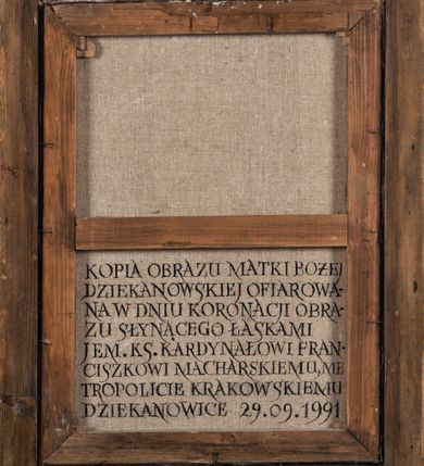 Zdjęcie nr 5: Obraz w kształcie stojącego prostokąta, ujęty złoconą, profilowaną ramą. W centrum kompozycji ukazana frontalnie, w popiersiu Matka Boska z Dzieciątkiem na tle obłoków, z których wyłaniają się uskrzydlone główki anielskie. Maria przedstawiona jako młoda kobieta z głową pochyloną w lewo. Na lewym ramieniu podtrzymuje siedzące Dzieciątko, prawą dłonią wskazuje na nie. Twarz Matki Boskiej owalna o dużych oczach i długim, prostym nosie. Włosy ciemnobrązowe, schowane pod granatowym płaszczem zarzuconym na głowę. Maria ubrana jest w czerwoną suknię z długimi rękawami wykończoną złotą lamówką oraz obszerny płaszcz spięty pod szyją ozdobną klamrą. Płaszcz wykończony jest złotą taśmą i dekorowany motywem złotego krzyża. Wokół głowy Marii widoczny jest żółto-niebieski nimb. Dzieciątko zwrócone w kierunku Matki Boskiej, ubrane w czerwoną tunikę z długimi rękawami wykończoną wąską, złota lamówką oraz złoty płaszcz. Prawą ręką wykonuje gest błogosławieństwa, lewą wspiera na jabłku królewskim. Spod szat widoczne są bose stopy Jezusa. Kolorystyka obrazu jasna, pastelowa. Na odwrociu napis: „KOPIA OBRAZU MATKI BOŻEJ / DZIEKANOWSKIEJ OFIAROWA- / NA W DNIU KORONACJI OBRA- / ZU SŁYNĄCEGO ŁASKAMI / JEM. KS(IĘDZU) KARDYNAŁOWI FRAN-/ CISZKOWI MACHARSKIEMU, ME- / TROPOLICIE KRAKOWSKIEMU / DZIEKANOWICE 29.09.1991”