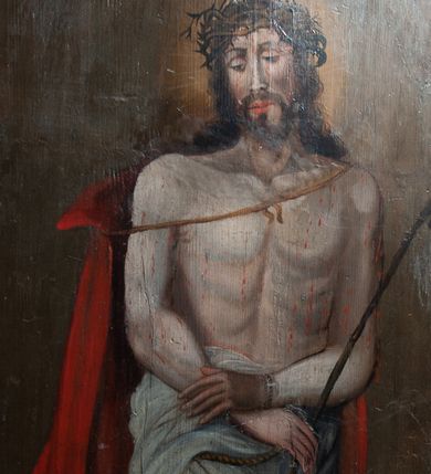 Zdjęcie nr 1: Obraz w kształcie stojącego prostokąta zamkniętego łukiem półkolistym. W centrum kompozycji przedstawiony Chrystus w typie Ecce Homo. Postać ukazana w pozycji stojącej, frontalnie z głową zwróconą nieznacznie w prawo. Ręce skrzyżowane na wysokości bioder, w prawej dłoni trzyma trzcinę. Chrystus przedstawiony jako młody mężczyzna o pociągłej twarzy, długich brązowych włosach i krótkim zaroście. Wzrok skierowany w dół. Na głowie Zbawiciela umieszczona cierniowa korona, a wokół niej świetlisty nimb. Tors nagi, wokół bioder udrapowane białe perizonium, na ramiona luźno narzucony czerwony płaszcz. Na drugim planie, z lewej strony kompozycji ukazany kamienny postument zwieńczony profilowanym gzymsem. Tło jednolite, ciemnobrązowe. 
