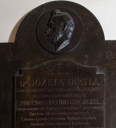 Zdjęcie nr 1: Epitafium w formie stojącego prostokąta, z uszkami, fazowanymi krawędziami bocznymi, zwieńczone łukiem półkolistym, nadwieszonym. W górnej części okrągły medalion z głową zmarłego, ukazanego z profilu, zwróconego w prawo i sygnaturą „M[ichał] Korpal”. W dolnej płyta z inskrypcją „Czci i Pamięci / D(okto)ra JÓZEFA DIETLA / KAWALERA ORDERÓW FRANCISZKA JÓZEFA I ŻELAZNEJ KORONY, / KOMANDORA ORDERU GRZEGORZA VII, / PROFESORA i REKTORA UNIW(ERSYTETU) JAGIELL(OŃSKIEGO), / którego staraniem język ojczysty w wykładach przywrócony, / Dyrektora Kliniki chorób wewnętrznych, / Członka czynnego i Dyrektora Wydziału przyrodn(iczego)  / Akademii Umiejętności w Krakowie, / Prezesa i Członka honorowego licznych Towarzystw lekarskich, / naukowych i humanitarnych w kraju i za granicą, / Wskrzesiciela zdrojowisk krajowych, / Autora wielu cennych dzieł lekarskich i pedagogicznych / i. t. d. i. t. d. / Posła na Sejm kraj(owy), Członka Izby Panów austr(yjackich) Rady Państwa, / pierwszego Prezydenta miasta Krakowa po objęciu samorządu, / Męża nieskazitelnego charakteru, wielkiej wiedzy i miłości / ojczyzny. / *1804. r(oku) †1878 r(oku) / WDZIĘCZNA RODZINA NAPIS TEN POŚWIĘCA.”
