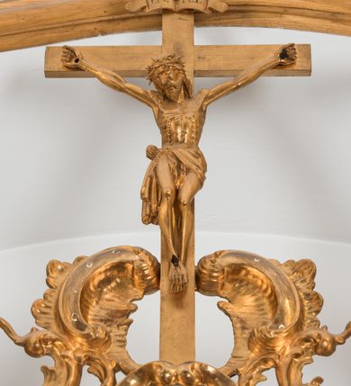 Zdjęcie nr 5: Na brązowym tle, z kolumną w lewej części kompozycji i lekko rozjaśnionymi obłokami, ukazany św. Jan Kanty klęczący przed siedzącą w chmurach Matką Boską z Dzieciątkiem i stojącym przed klęcznikiem aniołem. Święty spoczywa na klęczniku z otwartą księgą, ukazany jest w trzech czwartych, zwrócony w swoją lewą stronę, lewą ręką złożoną na piersi, a z prawą lekko uniesioną, z otwartą dłonią skierowaną w stronę Matki Boskiej. Jego twarz jest pociągła, oczy wydatne, uniesione w kierunku Marii. Jego nos jest długi, czoło wysokie, głowa okolona krótkimi, brązowymi włosami, a twarz krótką brodą z krótkimi wąsami. Wokół głowy aplikowana gloria z promieni o zróżnicowanej długości. Święty jest ubrany w długą uniwersytecką togę z białym plastronem. Maria ukazana frontalnie, w pozycji siedzącej, trzyma na kolanach stojące Dzieciątko. Jej twarz jest łagodna, oczy migdałowate, nos wydatny, usta drobne, włosy długie, brązowe, opadające na plecy. Ubrana w różową suknię i niebieski płaszcz okrywający ramiona i kolana. Jezus przedstawiony jest w trzech czwartych, niemal nagi, okryty z przodu i tyłu białą tkaniną, o twarzy okrągłej, z krótkimi włosami i pulchnej dziecięcej sylwecie. Nad głowami Marii i Jezusa utworzone ze złoconych promieni korony. Przed świętym stoi anioł, ukazany niemalże od tyłu, w pozycji stojącej, z lekko zgiętą lewą nogą. Ubrany jest w czerwoną, rozwianą, drobno marszczoną suknię, z głową zwróconą w kierunku świętego, z prawą ręką uniesioną, wskazuje palcem na Matkę Boską z Dzieciątkiem. Z obu stron Matki Boskiej uskrzydlone głowy aniołów wyłaniające się z obłoków. Obraz utrzymany w ciemnej tonacji kolorystycznej, z silnymi rozświetlonymi akcentami brązów, czerni, czerwieni i błękitów. Na odwrocie blachy wyryta inskrypcja: „Poninski 1778”. 