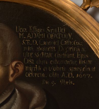Zdjęcie nr 4: Obraz w kształcie owalu, w profilowanej ramie, zwieńczonej motywem rocaille'a. Na obrazie mężczyzna ukazany w trzech czwartych, do pasa, zwrócony w prawo, ubrany w togę z sobolowym, białym kołnierzem, z rękoma złożonymi w geście modlitwy. W prawej górnej części obrazu napis „Uera Effigies Serui Dei / M(agistri) ADAMI OPATOUŸ / S(anctae) Th(eologiae) D(octoris) Canonici Cath(edralis) Crac(oviensis) / mira abstine(n)tia Doctrina ac / vitae sa(n)ctitatae clarissimi. Eius / Ossa dum exhumaretur, instar/mijrha et violaru(m) spargebant / odorem. obiit A(nno) D(omini) 1647 / Die 9. (Novem)bris.”.