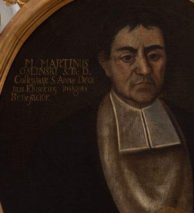 Zdjęcie nr 3: Obraz w kształcie owalu, w profilowanej złoconej ramie, zwieńczonej motywem rocaille'ów. Na obrazie ukazany do pasa, frontalnie mężczyzna, w todze z białymi befkami i mankietami obszytymi na czerwono, z załogą (pelerynką) zarzuconą na pierś. W prawej dłoni trzyma założony palcem wskazującym modlitewnik. Twarz modelowana sumarycznie, ukazana niemal frontalnie, z migdałowatymi oczami, szerokim, nosem i wąskimi ustami. Głowa z czarnymi, krótkimi włosami z przedziałkiem pośrodku, lekko zachodzącymi na uszy. W lewej górnej części obrazu napis „M(agister) MARTINUS / OSLINSKI S(anctae) Th(eologiae) D(octor) / Collegiatae S(anctae) Annae Deca/nus Eiusdemq(ue) insignis / Benefactor.”