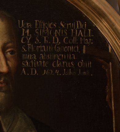 Zdjęcie nr 4: Obraz w kształcie owalu, w profilowanej ramie, zwieńczonej motywem rocaille’ów. Na obrazie mężczyzna ukazany do pasa, w trzech czwartych, zwrócony w lewo, w kierunku krucyfiksu ustawionego na stole z różańcem. Jest ubrany w togę z białym kołnierzem i białymi mankietami, z załogą (pelerynką), z rękami w geście modlitwy. Jego twarz jest pociągła, z długim nosem, krótkimi, jasnymi włosami i krótką brodą.  W prawej, górnej części obrazu napis „Vera Effigies Servi Dei / M(agistri) SIMONIS HALI/CY S(anctae) Th(eologiae) D(octoris) Coll(egii) Maj(oris) / s(ancti) Floriani Canonici, / mira abstinentia / sa(n)ctitate clarus, obiit / A(nno) D(omini) 1624. Idibus Junii.”.