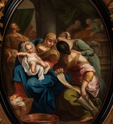 Zdjęcie nr 2: Kompozycja owalna w drewnianej, czarnej, profilowanej ramie. Na pierwszym planie ukazane trzy kobiety, z których jedna trzyma urodzoną właśnie Marię. Kobieta ukazana frontalnie, w pozycji siedzącej, ubrana w czerwoną suknię, niebieski płaszcz i brązową chustę na głowie, zwrócona w kierunku dwóch pozostałych piastunek. Na rękach trzyma dziecko, opatulone w białą pieluchę, z odsłoniętą klatką piersiową oraz nóżkami, z aureolą z gwiazd. Druga z kobiet ukazana z boku, z głową o czarnych włosach odwróconą od widza, z bandażem i dzbanem na wodę w rękach, ubrana w różową suknię i zieloną spódnicę. Trzecia z kobiet stojąca nieco z tyłu pochyla się nad nimi, ukazana z profilu, ubrana w zieloną suknię z włosami przewiązanymi chustą. W tle zarysowane szkicowo postacie: Joachima w brązowej sukni i białym płaszczu, z lewą ręką złożoną na piersi, prawą opuszczoną w dół, postać wyglądająca zza zielonej kotary oraz Anna leżąca na łożu, w zielonej sukni i białym welonie, przy której siedzi kobieta w brązowej sukni i białej chuście na głowie. Przed kobietami głęboka miedziana misa z wodą oraz fragment kołyski z poduszką. Pomieszczenie, w którym rozgrywa się scena, jest podzielone pośrodku kolumną, w lewej części widoczna półkolista arkada z kotarą, a po prawej pomieszczenie z łożem i podwieszoną pod sufitem, zieloną kotarą. Obok łoża Anny znajduje się stolik z okrągłym blatem, na którym leży miska z łyżką. 