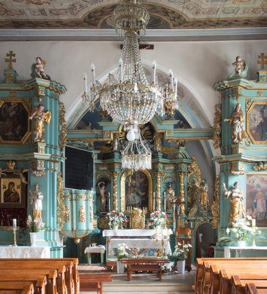 Zdjęcie nr 18: Kościół św. Kwiryna w Łapszach Niżnych usytuowany jest w centrum wsi w pobliżu rzeki Łapszanki. Teren przykościelny jest otoczony wysokim kamiennym, murem nakrytym cementowym daszkiem, jednospadowym, nachylonym na zewnątrz. W części wschodniej muru zlokalizowana jest brama, dostępna schodami, flankowana dwoma filarami, zwieńczonymi czterospadowym płaskim daszkiem i kulami. Analogiczne wejścia od strony zachodniej, północnej i południowej. W obrębie placu przykościelnego znajdują się resztki cmentarza w postaci nagrobków.

Kościół jest orientowany, murowany, otynkowany, jednonawowy z czworoboczną wieżą w fasadzie z prezbiterium zamkniętym trójbocznie. Prezbiterium nakryte sklepieniem krzyżowo-żebrowym, oddzielone od nawy ścianą arkady tęczowej o ostrołukowym zakończeniu. Nawa jest szersza, nakryta stropem. Do prezbiterium przylega od północny niewielka zakrystia na planie prostokąta, a także przylegająca do niej i do ściany nawy druga nowsza zakrystia. Z kolei przy południowej ścianie nawy znajduje się kruchta, zwana babińcem z wejściem do świątyni. Portal prowadzący z kruchty do kościoła ostrołukowy, kamienny, skromnie profilowany – dwa wałki i dwa żłobki. Portal zamknięty drzwiami ze starymi ćwiekowymi okuciami, malowany z wypisaną datą 1652. Na drzwiach napis: „Laudetur Santissimum Sacramentum 1652”. Z kolei na północnej ścianie prezbiterium portal malowany, iluzjonistyczny z wejściem do zakrystii. U góry napis: „PIETAS ET LITTERAE”. Na zachodniej ścianie nawy chór muzyczny wsparty na dwóch filarach z dostępem kręconymi, drewnianymi schodami od północy. 

Wnętrze oświetlają umieszczone w południowych ścianach nawy prostokątne, zamknięte półkoliście cztery okna oraz jedno od strony południowej w prezbiterium; w cztery podobne, małe okna umieszczone po jednym z każdej strony w najwyższej kondygnacji. Do kościoła prowadzi główne wejście od strony zachodniej oraz jedno przez kruchtę od południa i jedno od strony północnej przez zakrystię.

W zewnętrznej elewacji kościoła widoczny jest niewysoki, kamienny cokół, powyżej kościół otynkowany. Prezbiterium, niższe od nawy. Nawa nakryta dachem dwuspadowym z wieżą na sygnaturkę na wschodnim zakończeniu nawy. Do zachodniej fasady kościoła dostawiona jest wysoka założona na planie kwadratu wieża-dzwonnica. W dolnej kondygnacji na osi kościoła prostokątne wejście do kruchty, nakryte daszkiem. Hełm wieży baniasty z latarnią. Na zewnątrz przy apsydzie prezbiterium dwie skarpy złączone daszkiem tworzą wnękę, w której umieszczony jest stół ołtarzowy i grupa Ukrzyżowania tzw. kalwaryjka. Na południowej ścianie nawy znajdował się zegar słoneczny, obecnie pozostała tylko wskazówka po zamalowaniu podczas remontu ścian zewnętrznych.

