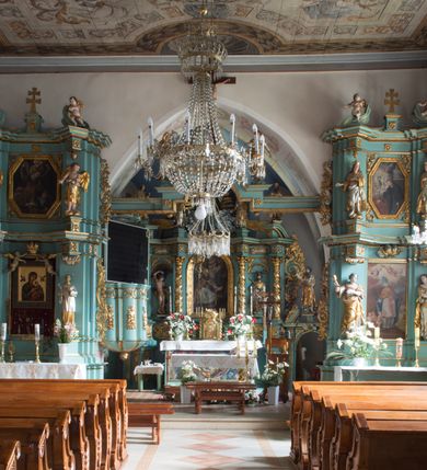 Zdjęcie nr 17: Kościół św. Kwiryna w Łapszach Niżnych usytuowany jest w centrum wsi w pobliżu rzeki Łapszanki. Teren przykościelny jest otoczony wysokim kamiennym, murem nakrytym cementowym daszkiem, jednospadowym, nachylonym na zewnątrz. W części wschodniej muru zlokalizowana jest brama, dostępna schodami, flankowana dwoma filarami, zwieńczonymi czterospadowym płaskim daszkiem i kulami. Analogiczne wejścia od strony zachodniej, północnej i południowej. W obrębie placu przykościelnego znajdują się resztki cmentarza w postaci nagrobków.

Kościół jest orientowany, murowany, otynkowany, jednonawowy z czworoboczną wieżą w fasadzie z prezbiterium zamkniętym trójbocznie. Prezbiterium nakryte sklepieniem krzyżowo-żebrowym, oddzielone od nawy ścianą arkady tęczowej o ostrołukowym zakończeniu. Nawa jest szersza, nakryta stropem. Do prezbiterium przylega od północny niewielka zakrystia na planie prostokąta, a także przylegająca do niej i do ściany nawy druga nowsza zakrystia. Z kolei przy południowej ścianie nawy znajduje się kruchta, zwana babińcem z wejściem do świątyni. Portal prowadzący z kruchty do kościoła ostrołukowy, kamienny, skromnie profilowany – dwa wałki i dwa żłobki. Portal zamknięty drzwiami ze starymi ćwiekowymi okuciami, malowany z wypisaną datą 1652. Na drzwiach napis: „Laudetur Santissimum Sacramentum 1652”. Z kolei na północnej ścianie prezbiterium portal malowany, iluzjonistyczny z wejściem do zakrystii. U góry napis: „PIETAS ET LITTERAE”. Na zachodniej ścianie nawy chór muzyczny wsparty na dwóch filarach z dostępem kręconymi, drewnianymi schodami od północy. 

Wnętrze oświetlają umieszczone w południowych ścianach nawy prostokątne, zamknięte półkoliście cztery okna oraz jedno od strony południowej w prezbiterium; w cztery podobne, małe okna umieszczone po jednym z każdej strony w najwyższej kondygnacji. Do kościoła prowadzi główne wejście od strony zachodniej oraz jedno przez kruchtę od południa i jedno od strony północnej przez zakrystię.

W zewnętrznej elewacji kościoła widoczny jest niewysoki, kamienny cokół, powyżej kościół otynkowany. Prezbiterium, niższe od nawy. Nawa nakryta dachem dwuspadowym z wieżą na sygnaturkę na wschodnim zakończeniu nawy. Do zachodniej fasady kościoła dostawiona jest wysoka założona na planie kwadratu wieża-dzwonnica. W dolnej kondygnacji na osi kościoła prostokątne wejście do kruchty, nakryte daszkiem. Hełm wieży baniasty z latarnią. Na zewnątrz przy apsydzie prezbiterium dwie skarpy złączone daszkiem tworzą wnękę, w której umieszczony jest stół ołtarzowy i grupa Ukrzyżowania tzw. kalwaryjka. Na południowej ścianie nawy znajdował się zegar słoneczny, obecnie pozostała tylko wskazówka po zamalowaniu podczas remontu ścian zewnętrznych.

