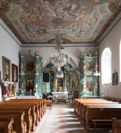 Zdjęcie nr 16: Kościół św. Kwiryna w Łapszach Niżnych usytuowany jest w centrum wsi w pobliżu rzeki Łapszanki. Teren przykościelny jest otoczony wysokim kamiennym, murem nakrytym cementowym daszkiem, jednospadowym, nachylonym na zewnątrz. W części wschodniej muru zlokalizowana jest brama, dostępna schodami, flankowana dwoma filarami, zwieńczonymi czterospadowym płaskim daszkiem i kulami. Analogiczne wejścia od strony zachodniej, północnej i południowej. W obrębie placu przykościelnego znajdują się resztki cmentarza w postaci nagrobków.

Kościół jest orientowany, murowany, otynkowany, jednonawowy z czworoboczną wieżą w fasadzie z prezbiterium zamkniętym trójbocznie. Prezbiterium nakryte sklepieniem krzyżowo-żebrowym, oddzielone od nawy ścianą arkady tęczowej o ostrołukowym zakończeniu. Nawa jest szersza, nakryta stropem. Do prezbiterium przylega od północny niewielka zakrystia na planie prostokąta, a także przylegająca do niej i do ściany nawy druga nowsza zakrystia. Z kolei przy południowej ścianie nawy znajduje się kruchta, zwana babińcem z wejściem do świątyni. Portal prowadzący z kruchty do kościoła ostrołukowy, kamienny, skromnie profilowany – dwa wałki i dwa żłobki. Portal zamknięty drzwiami ze starymi ćwiekowymi okuciami, malowany z wypisaną datą 1652. Na drzwiach napis: „Laudetur Santissimum Sacramentum 1652”. Z kolei na północnej ścianie prezbiterium portal malowany, iluzjonistyczny z wejściem do zakrystii. U góry napis: „PIETAS ET LITTERAE”. Na zachodniej ścianie nawy chór muzyczny wsparty na dwóch filarach z dostępem kręconymi, drewnianymi schodami od północy. 

Wnętrze oświetlają umieszczone w południowych ścianach nawy prostokątne, zamknięte półkoliście cztery okna oraz jedno od strony południowej w prezbiterium; w cztery podobne, małe okna umieszczone po jednym z każdej strony w najwyższej kondygnacji. Do kościoła prowadzi główne wejście od strony zachodniej oraz jedno przez kruchtę od południa i jedno od strony północnej przez zakrystię.

W zewnętrznej elewacji kościoła widoczny jest niewysoki, kamienny cokół, powyżej kościół otynkowany. Prezbiterium, niższe od nawy. Nawa nakryta dachem dwuspadowym z wieżą na sygnaturkę na wschodnim zakończeniu nawy. Do zachodniej fasady kościoła dostawiona jest wysoka założona na planie kwadratu wieża-dzwonnica. W dolnej kondygnacji na osi kościoła prostokątne wejście do kruchty, nakryte daszkiem. Hełm wieży baniasty z latarnią. Na zewnątrz przy apsydzie prezbiterium dwie skarpy złączone daszkiem tworzą wnękę, w której umieszczony jest stół ołtarzowy i grupa Ukrzyżowania tzw. kalwaryjka. Na południowej ścianie nawy znajdował się zegar słoneczny, obecnie pozostała tylko wskazówka po zamalowaniu podczas remontu ścian zewnętrznych.

