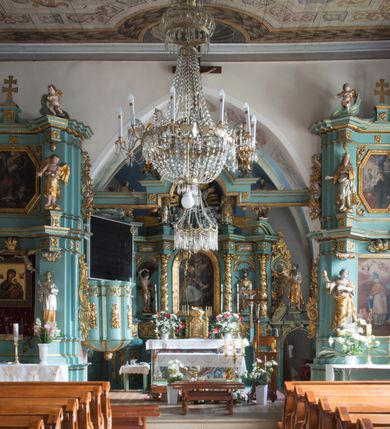 Zdjęcie nr 3: Kościół św. Kwiryna w Łapszach Niżnych usytuowany jest w centrum wsi w pobliżu rzeki Łapszanki. Teren przykościelny jest otoczony wysokim kamiennym, murem nakrytym cementowym daszkiem, jednospadowym, nachylonym na zewnątrz. W części wschodniej muru zlokalizowana jest brama, dostępna schodami, flankowana dwoma filarami, zwieńczonymi czterospadowym płaskim daszkiem i kulami. Analogiczne wejścia od strony zachodniej, północnej i południowej. W obrębie placu przykościelnego znajdują się resztki cmentarza w postaci nagrobków.

Kościół jest orientowany, murowany, otynkowany, jednonawowy z czworoboczną wieżą w fasadzie z prezbiterium zamkniętym trójbocznie. Prezbiterium nakryte sklepieniem krzyżowo-żebrowym, oddzielone od nawy ścianą arkady tęczowej o ostrołukowym zakończeniu. Nawa jest szersza, nakryta stropem. Do prezbiterium przylega od północny niewielka zakrystia na planie prostokąta, a także przylegająca do niej i do ściany nawy druga nowsza zakrystia. Z kolei przy południowej ścianie nawy znajduje się kruchta, zwana babińcem z wejściem do świątyni. Portal prowadzący z kruchty do kościoła ostrołukowy, kamienny, skromnie profilowany – dwa wałki i dwa żłobki. Portal zamknięty drzwiami ze starymi ćwiekowymi okuciami, malowany z wypisaną datą 1652. Na drzwiach napis: „Laudetur Santissimum Sacramentum 1652”. Z kolei na północnej ścianie prezbiterium portal malowany, iluzjonistyczny z wejściem do zakrystii. U góry napis: „PIETAS ET LITTERAE”. Na zachodniej ścianie nawy chór muzyczny wsparty na dwóch filarach z dostępem kręconymi, drewnianymi schodami od północy. 

Wnętrze oświetlają umieszczone w południowych ścianach nawy prostokątne, zamknięte półkoliście cztery okna oraz jedno od strony południowej w prezbiterium; w cztery podobne, małe okna umieszczone po jednym z każdej strony w najwyższej kondygnacji. Do kościoła prowadzi główne wejście od strony zachodniej oraz jedno przez kruchtę od południa i jedno od strony północnej przez zakrystię.

W zewnętrznej elewacji kościoła widoczny jest niewysoki, kamienny cokół, powyżej kościół otynkowany. Prezbiterium, niższe od nawy. Nawa nakryta dachem dwuspadowym z wieżą na sygnaturkę na wschodnim zakończeniu nawy. Do zachodniej fasady kościoła dostawiona jest wysoka założona na planie kwadratu wieża-dzwonnica. W dolnej kondygnacji na osi kościoła prostokątne wejście do kruchty, nakryte daszkiem. Hełm wieży baniasty z latarnią. Na zewnątrz przy apsydzie prezbiterium dwie skarpy złączone daszkiem tworzą wnękę, w której umieszczony jest stół ołtarzowy i grupa Ukrzyżowania tzw. kalwaryjka. Na południowej ścianie nawy znajdował się zegar słoneczny, obecnie pozostała tylko wskazówka po zamalowaniu podczas remontu ścian zewnętrznych.

