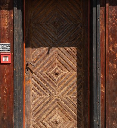 Zdjęcie nr 21: Kościół drewniany, o konstrukcji ramowej, na kamiennej podmurówce, elewacje jednolite, szalowane z listwowaniem o układzie pionowym z gzymsami pseudoarkadkowymi. Wieża zachodnia o konstrukcji słupowej, z szalunkiem o układzie poziomym z fryzem arkadkowym w górnej partii. Więźba dachowa drewniana, krokwiowa. Budynek na betonowym podmurowaniu przesłoniętym daszkiem gontowym. Kościół orientowany, trójnawowy, na rzucie wydłużonego krzyża, z płytkim transeptem, prezbiterium zakończone trójbocznie, z zakrystią przylegającą od południa, na skrzyżowaniu naw kopuła. Od zachodu wieża czterokondygnacyjna, na planie kwadratu przechodzącego w kwadrat o coraz bardziej ściętych narożach, ujęta dwiema kruchtami na rzucie kwadratu. Wnętrze o układzie bazylikowym, nawy podzielone smukłymi, żeliwnymi kolumienkami. Pomiędzy nawą a prezbiterium otwór tęczowy w formie kwadratu o ściętych narożach. Parapet chóru muzycznego w zachodniej części kościoła podparty na czterech kolumienkach. Nawa główna nakryta stropem z widocznymi elementami konstrukcji więźby, nawy boczne przekryte pułapami deskowymi. Posadzka z płyt kamiennych. Elewacja frontowa w formie wieży z dwoma kruchtami. Na każdej z trzech osi wejście z dwuskrzydłowymi drzwiami klepkowymi o układzie rombowym, z oknami w partii szczytu, nakryte daszkami okapowymi. Nad wejściem głównym żeliwna tabliczka z napisem „E(RZ)H(ERZOG) / ALBRECHT / 1888”. Na każdej kondygnacji wieży okna w formie stojącego prostokąta zwieńczone daszkami pulpitowymi, na pierwszej jedno, na drugiej trzy, na trzeciej cztery, na czwartej osiem. W elewacji północnej i południowej cztery podwójne otwory okienne w formie stojącego prostokąta o ściętych górnych narożach w partii naw bocznych oraz pięć okienek w formie leżącego prostokąta w partii nawy głównej. W elewacji południowej wejście z dwuskrzydłowymi drzwiami klepkowymi o układzie rombowym. Na osi skrzydeł transeptu po jednym otworze okiennym w formie stojącego prostokąta o ściętych górnych narożach. Na ścianie wschodniej prezbiterium Ogrójec w formie grupy Ukrzyżowania nakrytej daszkiem pulpitowym, flankowany dwoma otworami okiennymi w kształcie stojącego prostokąta o ściętych górnych narożach. Nawa główna nakryta dachem dwuspadowym. W połowie długości dachu oraz na skrzyżowaniu naw wznoszą się ponad kalenicą wieżyczki na sygnaturkę, na ośmiobocznym obitym blachą trzonie, z latarniami zwieńczonymi cebulastymi hełmami. Nad nawami bocznymi dachy pulpitowe, ramiona transeptu nakrywają dachy naczółkowe. Wieża zwieńczona dachem wieżowym, ośmiobocznym, z iglicą zakończoną krzyżem. 


