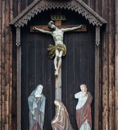 Zdjęcie nr 57: Kościół drewniany o konstrukcji zrębowej, elewacje jednolite, szalowane z listwowaniem, wzmocnione lisicami, wieża o konstrukcji słupowej. Więźba dachowa drewniana, krokwiowa. Budynek na kamiennym podmurowaniu przesłoniętym daszkiem gontowym. Kościół orientowany, jednonawowy z dwiema kaplicami o charakterze transeptu zamkniętymi wielobocznie, na planie krzyża łacińskiego, o węższym prezbiterium zamkniętym trójbocznie. Do wschodniej ściany prezbiterium przylega ogrójec w formie kapliczki, od północy zakrystia na planie prostokąta. Na skrzyżowaniu nawy z południowym ramieniem transeptu kruchta na planie prostokąta. Od zachodu do nawy przylega wieża na planie kwadratu, otoczona sobotami. Prezbiterium i nawa nakryte pozornym sklepieniem tej samej szerokości, obwiedzionym dużym, profilowanym gzymsem podtrzymywanym w nawie przez dwie pary filarów o kanelowanych trzonach, na cokołach. Sklepieniu nawy głównej towarzyszą płaskie i niższe stropy z fasetami w przestrzeniach bocznych. Ściany boczne nawy zwieńczone profilowanym gzymsem. Pomiędzy nawą a prezbiterium otwór tęczowy w formie odcinkowej arkady podtrzymywanej przez filary o kanelowanych trzonach z belką o falistym zarysie. Kaplice boczne otwarte do nawy odcinkowymi arkadami podtrzymywanymi przez filary o kanelowanych trzonach, na cokołach. Parapet chóru muzycznego w zachodniej części nawy, o wybrzuszonej środkowej części, podparty na dwóch filarach o kanelowanych trzonach, na cokołach. Posadzka z płyt ceramicznych. Elewacja frontowa w postaci wieży otoczonej sobotami. Na osi frontowej ściany sobót płytka kruchta zwieńczona gzymsem z przyczółkiem wypełnionym motywem „słoneczka”, przykryta dwuspadowym dachem. Drzwi dwuskrzydłowe, drewniane z okuciami. Korpus wieży podzielony poziomo daszkiem okapowym w dwóch trzecich wysokości, na froncie okno. W dolnej części małe otwory dzwonne z trzech stron, w górnej części duże otwory dzwonne z czterech stron. Wieża zwieńczona hełmem baniastym z latarnią. Ściany sobót szalowane z poziomym listwowaniem, przekryte mansardowym dachem gontowym, na północnej i południowej ścianie dwie pary okien w formie leżącego prostokąta zamkniętego łukiem odcinkowym. W elewacji południowej cztery otwory okienne w formie stojącego prostokąta zamkniętego łukiem odcinkowym, w partii prezbiterium z witrażami. Na elewacji wschodniej ogrójec w formie nadwieszonej kapliczki nakrytej dwuspadowym daszkiem z grupą Ukrzyżowania. W elewacji północnej dwa otwory okienne w formie stojącego prostokąta zamkniętego łukiem odcinkowym. W zakrystii małe kwadratowe okienko. W obu ramionach transeptu analogiczne jak w elewacjach otwory okienne na wschodniej i zachodniej ścianie. Kościół nakryty dachami gontowymi, wyższym nad nawą, niższym nad prezbiterium, dwuspadowym nad nawą oraz wielospadowym nad prezbiterium i ramionami transeptu; nad zakrystią i kruchtą boczną dachy dwuspadowe. W połowie długości dachu, nad nawą, od strony prezbiterium wznosi się ponad kalenicą wieżyczka na sygnaturkę, obita blachą, na ośmiobocznym trzonie, z latarnią zwieńczoną niewielkim baniastym hełmem z latarnią.
