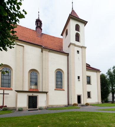 Zdjęcie nr 31: Kościół jest jednonawowy, trójprzęsłowy, z płytkimi kaplicami tworzącymi pseudotransept i jednoprzęsłowym prezbiterium zakończonym apsydą. Do prezbiterium przylegają dwa aneksy mieszące w przyziemiu zakrystię i skarbczyk, a na piętrze empory otwarte na prezbiterium. Do nawy od południa dostawiona jest kruchta. W naroża między kaplicami a nawą wstawiono dwie wieże-dzwonnice z klatkami schodowymi prowadzącymi na empory. Nawa jest rozczłonkowana płaskimi, szerokimi pilastrami toskańskimi, a nakryta sklepieniem kolebkowym z lunetami; prezbiterium przykryte sklepieniem kolebkowym z żebrami spływającymi na wsporniki, apsyda sklepieniem parasolowatym.  Prezbiterium ujęte dwiema głębokimi, półkoliście zamkniętymi wnękami, nad którymi parapety empor z ślepymi arkadkami z balasów jenolalkowych i łuków półkolistych. Wnętrze oświetlają wysokie i szerokie okna zamknięte półkoliście. W aneksach przy prezbiterium i w emporach znajdują się okna prostokątne. Fasada dwustrefowa, trójosiowa, ale osie i strefy wyznaczone jedynie przez okna, drzwi i nisze, zamknięta trójkątnie.    
Portal prostokątnych drzwi utworzony z pary żłobkowanych, toskańskich pilastrów, podtrzymujących belkowanie z trójkątnym przyczółkiem. Fryz belkowania ozdobiony tryglifami z łezkami i metopami w kształcie rozet i talerzy, a przyczółek kostkowaniem. Nad portalem okno w głębokim rozglifieniu, w kształcie prostokąta zamkniętego półkoliście. Po bokach portalu i okna głębokie nisze ujęte od dołu i góry odcinkami gzymsu. Zewnętrzne elewacje ujęte częściowo szkarpami, częściowo lizenami. W wieżach wejścia do kościoła i na klatki schodowe oraz niewielkie okienka w klatce schodowej i prześwity zamknięte półkoliście w dzwonnicach. Dachy dwuspadowe, na wieżach czterospadowe, nad nawą, wieżami i aneksami przy prezbiterium kryte dachówką, nad prezbiterium blachą. Na dachu wieżyczka na sygnaturkę. 
