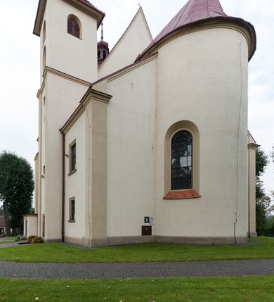 Zdjęcie nr 7: Kościół jest jednonawowy, trójprzęsłowy, z płytkimi kaplicami tworzącymi pseudotransept i jednoprzęsłowym prezbiterium zakończonym apsydą. Do prezbiterium przylegają dwa aneksy mieszące w przyziemiu zakrystię i skarbczyk, a na piętrze empory otwarte na prezbiterium. Do nawy od południa dostawiona jest kruchta. W naroża między kaplicami a nawą wstawiono dwie wieże-dzwonnice z klatkami schodowymi prowadzącymi na empory. Nawa jest rozczłonkowana płaskimi, szerokimi pilastrami toskańskimi, a nakryta sklepieniem kolebkowym z lunetami; prezbiterium przykryte sklepieniem kolebkowym z żebrami spływającymi na wsporniki, apsyda sklepieniem parasolowatym.  Prezbiterium ujęte dwiema głębokimi, półkoliście zamkniętymi wnękami, nad którymi parapety empor z ślepymi arkadkami z balasów jenolalkowych i łuków półkolistych. Wnętrze oświetlają wysokie i szerokie okna zamknięte półkoliście. W aneksach przy prezbiterium i w emporach znajdują się okna prostokątne. Fasada dwustrefowa, trójosiowa, ale osie i strefy wyznaczone jedynie przez okna, drzwi i nisze, zamknięta trójkątnie.    
Portal prostokątnych drzwi utworzony z pary żłobkowanych, toskańskich pilastrów, podtrzymujących belkowanie z trójkątnym przyczółkiem. Fryz belkowania ozdobiony tryglifami z łezkami i metopami w kształcie rozet i talerzy, a przyczółek kostkowaniem. Nad portalem okno w głębokim rozglifieniu, w kształcie prostokąta zamkniętego półkoliście. Po bokach portalu i okna głębokie nisze ujęte od dołu i góry odcinkami gzymsu. Zewnętrzne elewacje ujęte częściowo szkarpami, częściowo lizenami. W wieżach wejścia do kościoła i na klatki schodowe oraz niewielkie okienka w klatce schodowej i prześwity zamknięte półkoliście w dzwonnicach. Dachy dwuspadowe, na wieżach czterospadowe, nad nawą, wieżami i aneksami przy prezbiterium kryte dachówką, nad prezbiterium blachą. Na dachu wieżyczka na sygnaturkę. 
