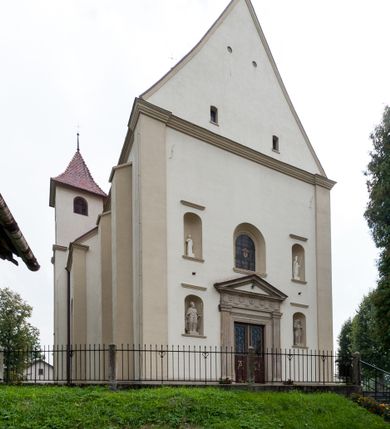 Zdjęcie nr 30: Kościół jest jednonawowy, trójprzęsłowy, z płytkimi kaplicami tworzącymi pseudotransept i jednoprzęsłowym prezbiterium zakończonym apsydą. Do prezbiterium przylegają dwa aneksy mieszące w przyziemiu zakrystię i skarbczyk, a na piętrze empory otwarte na prezbiterium. Do nawy od południa dostawiona jest kruchta. W naroża między kaplicami a nawą wstawiono dwie wieże-dzwonnice z klatkami schodowymi prowadzącymi na empory. Nawa jest rozczłonkowana płaskimi, szerokimi pilastrami toskańskimi, a nakryta sklepieniem kolebkowym z lunetami; prezbiterium przykryte sklepieniem kolebkowym z żebrami spływającymi na wsporniki, apsyda sklepieniem parasolowatym.  Prezbiterium ujęte dwiema głębokimi, półkoliście zamkniętymi wnękami, nad którymi parapety empor z ślepymi arkadkami z balasów jenolalkowych i łuków półkolistych. Wnętrze oświetlają wysokie i szerokie okna zamknięte półkoliście. W aneksach przy prezbiterium i w emporach znajdują się okna prostokątne. Fasada dwustrefowa, trójosiowa, ale osie i strefy wyznaczone jedynie przez okna, drzwi i nisze, zamknięta trójkątnie.    
Portal prostokątnych drzwi utworzony z pary żłobkowanych, toskańskich pilastrów, podtrzymujących belkowanie z trójkątnym przyczółkiem. Fryz belkowania ozdobiony tryglifami z łezkami i metopami w kształcie rozet i talerzy, a przyczółek kostkowaniem. Nad portalem okno w głębokim rozglifieniu, w kształcie prostokąta zamkniętego półkoliście. Po bokach portalu i okna głębokie nisze ujęte od dołu i góry odcinkami gzymsu. Zewnętrzne elewacje ujęte częściowo szkarpami, częściowo lizenami. W wieżach wejścia do kościoła i na klatki schodowe oraz niewielkie okienka w klatce schodowej i prześwity zamknięte półkoliście w dzwonnicach. Dachy dwuspadowe, na wieżach czterospadowe, nad nawą, wieżami i aneksami przy prezbiterium kryte dachówką, nad prezbiterium blachą. Na dachu wieżyczka na sygnaturkę. 

