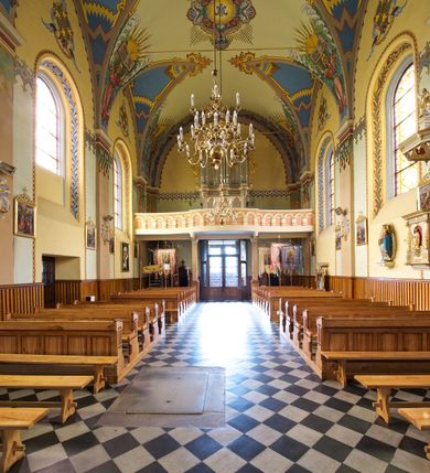 Zdjęcie nr 17: Kościół jest jednonawowy, trójprzęsłowy, z płytkimi kaplicami tworzącymi pseudotransept i jednoprzęsłowym prezbiterium zakończonym apsydą. Do prezbiterium przylegają dwa aneksy mieszące w przyziemiu zakrystię i skarbczyk, a na piętrze empory otwarte na prezbiterium. Do nawy od południa dostawiona jest kruchta. W naroża między kaplicami a nawą wstawiono dwie wieże-dzwonnice z klatkami schodowymi prowadzącymi na empory. Nawa jest rozczłonkowana płaskimi, szerokimi pilastrami toskańskimi, a nakryta sklepieniem kolebkowym z lunetami; prezbiterium przykryte sklepieniem kolebkowym z żebrami spływającymi na wsporniki, apsyda sklepieniem parasolowatym.  Prezbiterium ujęte dwiema głębokimi, półkoliście zamkniętymi wnękami, nad którymi parapety empor z ślepymi arkadkami z balasów jenolalkowych i łuków półkolistych. Wnętrze oświetlają wysokie i szerokie okna zamknięte półkoliście. W aneksach przy prezbiterium i w emporach znajdują się okna prostokątne. Fasada dwustrefowa, trójosiowa, ale osie i strefy wyznaczone jedynie przez okna, drzwi i nisze, zamknięta trójkątnie.    
Portal prostokątnych drzwi utworzony z pary żłobkowanych, toskańskich pilastrów, podtrzymujących belkowanie z trójkątnym przyczółkiem. Fryz belkowania ozdobiony tryglifami z łezkami i metopami w kształcie rozet i talerzy, a przyczółek kostkowaniem. Nad portalem okno w głębokim rozglifieniu, w kształcie prostokąta zamkniętego półkoliście. Po bokach portalu i okna głębokie nisze ujęte od dołu i góry odcinkami gzymsu. Zewnętrzne elewacje ujęte częściowo szkarpami, częściowo lizenami. W wieżach wejścia do kościoła i na klatki schodowe oraz niewielkie okienka w klatce schodowej i prześwity zamknięte półkoliście w dzwonnicach. Dachy dwuspadowe, na wieżach czterospadowe, nad nawą, wieżami i aneksami przy prezbiterium kryte dachówką, nad prezbiterium blachą. Na dachu wieżyczka na sygnaturkę. 
