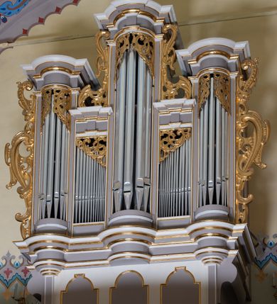 Zdjęcie nr 29: Kościół jest jednonawowy, trójprzęsłowy, z płytkimi kaplicami tworzącymi pseudotransept i jednoprzęsłowym prezbiterium zakończonym apsydą. Do prezbiterium przylegają dwa aneksy mieszące w przyziemiu zakrystię i skarbczyk, a na piętrze empory otwarte na prezbiterium. Do nawy od południa dostawiona jest kruchta. W naroża między kaplicami a nawą wstawiono dwie wieże-dzwonnice z klatkami schodowymi prowadzącymi na empory. Nawa jest rozczłonkowana płaskimi, szerokimi pilastrami toskańskimi, a nakryta sklepieniem kolebkowym z lunetami; prezbiterium przykryte sklepieniem kolebkowym z żebrami spływającymi na wsporniki, apsyda sklepieniem parasolowatym.  Prezbiterium ujęte dwiema głębokimi, półkoliście zamkniętymi wnękami, nad którymi parapety empor z ślepymi arkadkami z balasów jenolalkowych i łuków półkolistych. Wnętrze oświetlają wysokie i szerokie okna zamknięte półkoliście. W aneksach przy prezbiterium i w emporach znajdują się okna prostokątne. Fasada dwustrefowa, trójosiowa, ale osie i strefy wyznaczone jedynie przez okna, drzwi i nisze, zamknięta trójkątnie.    
Portal prostokątnych drzwi utworzony z pary żłobkowanych, toskańskich pilastrów, podtrzymujących belkowanie z trójkątnym przyczółkiem. Fryz belkowania ozdobiony tryglifami z łezkami i metopami w kształcie rozet i talerzy, a przyczółek kostkowaniem. Nad portalem okno w głębokim rozglifieniu, w kształcie prostokąta zamkniętego półkoliście. Po bokach portalu i okna głębokie nisze ujęte od dołu i góry odcinkami gzymsu. Zewnętrzne elewacje ujęte częściowo szkarpami, częściowo lizenami. W wieżach wejścia do kościoła i na klatki schodowe oraz niewielkie okienka w klatce schodowej i prześwity zamknięte półkoliście w dzwonnicach. Dachy dwuspadowe, na wieżach czterospadowe, nad nawą, wieżami i aneksami przy prezbiterium kryte dachówką, nad prezbiterium blachą. Na dachu wieżyczka na sygnaturkę. 
