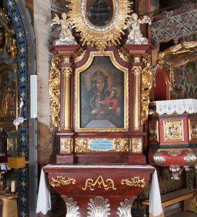 Zdjęcie nr 1: Ołtarz przyścienny, architektoniczny, jednokondygnacyjny, jednoosiowy, ze zwieńczeniem. Mensa w typie sarkofagowym z kamiennym portatylem, dekorowana w dolnej partii srebrnymi liśćmi akantu, a w górnej pośrodku płaskorzeźbiony monogram maryjny ujęty plakietami ornamentalnymi z kształtów nawiązujących do motywu rocaille’a; całość mensy groszkowana. Retabulum na cokole o wysuniętych bokach, ujęte parą kolumn o kapitelach akantowych i gładkich trzonach, wspierających fragmenty belkowania z silnie wysuniętymi fryzem i gzymsem. Pola cokołu retabulum zdobione motywem wici akantowej, z kartuszem w kształcie leżącego owalu pośrodku z ciemnoniebieskim napisem na jasnoniebieskim tle „POMŃIK od NOWIEŃA / OŁTARZA ZPOŻYCZKI HARKLOwy / dodał Utrzymańie przy tej Robocie Stanisław Plewa. / w. 1856”. Oś środkową nastawy wypełnia pole w kształcie stojącego prostokąta o wklęsłych górnych narożach, ujęte profilowaną, częściowo złoconą ramą, z motywem liści laurowych. W polu obraz z przedstawieniem Madonny z Dzieciątkiem. Kondygnację flankują ażurowe uszaki utworzone z bujnej, mięsistej wici akantu. Zwieńczenie tworzy owalne przedstawienie św. Kingi otoczone srebrnymi obłokami oraz glorią promienistą o promieniach różnej długości. Zwieńczenie flankuje para nagich aniołków posadowionych na srebrzonych chmurach, umieszczonych na fragmentach belkowania retabulum. 
Struktura polichromowana w kolorze brązowym. Partie detalu architektonicznego i ornamentyka złocone i srebrzone. 
