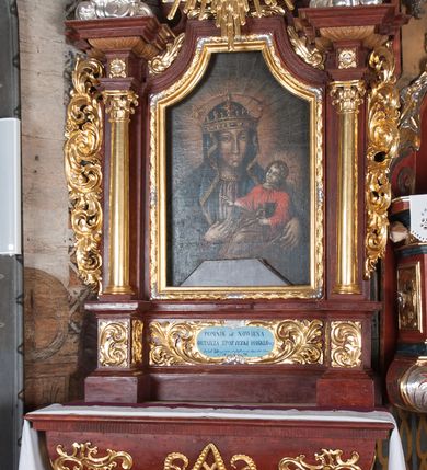 Zdjęcie nr 4: Ołtarz przyścienny, architektoniczny, jednokondygnacyjny, jednoosiowy, ze zwieńczeniem. Mensa w typie sarkofagowym z kamiennym portatylem, dekorowana w dolnej partii srebrnymi liśćmi akantu, a w górnej pośrodku płaskorzeźbiony monogram maryjny ujęty plakietami ornamentalnymi z kształtów nawiązujących do motywu rocaille’a; całość mensy groszkowana. Retabulum na cokole o wysuniętych bokach, ujęte parą kolumn o kapitelach akantowych i gładkich trzonach, wspierających fragmenty belkowania z silnie wysuniętymi fryzem i gzymsem. Pola cokołu retabulum zdobione motywem wici akantowej, z kartuszem w kształcie leżącego owalu pośrodku z ciemnoniebieskim napisem na jasnoniebieskim tle „POMŃIK od NOWIEŃA / OŁTARZA ZPOŻYCZKI HARKLOwy / dodał Utrzymańie przy tej Robocie Stanisław Plewa. / w. 1856”. Oś środkową nastawy wypełnia pole w kształcie stojącego prostokąta o wklęsłych górnych narożach, ujęte profilowaną, częściowo złoconą ramą, z motywem liści laurowych. W polu obraz z przedstawieniem Madonny z Dzieciątkiem. Kondygnację flankują ażurowe uszaki utworzone z bujnej, mięsistej wici akantu. Zwieńczenie tworzy owalne przedstawienie św. Kingi otoczone srebrnymi obłokami oraz glorią promienistą o promieniach różnej długości. Zwieńczenie flankuje para nagich aniołków posadowionych na srebrzonych chmurach, umieszczonych na fragmentach belkowania retabulum. 
Struktura polichromowana w kolorze brązowym. Partie detalu architektonicznego i ornamentyka złocone i srebrzone. 
