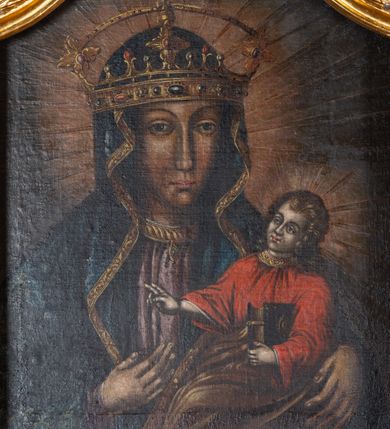 Zdjęcie nr 3: Obraz w kształcie stojącego prostokąta o wklęsłych górnych narożach. Madonna w typie Hodegetrii, przedstawiona frontalnie, w półpostaci. Głowa zwrócona lekko w lewo, twarz pociągła, o wyrazistych rysach, ciemnej karnacji, długim nosie, dużych oczach i drobnych ustach, na prawym policzku dwa równoległe, ukośnie biegnące nacięcia. Maria ubrana w jasnoróżową suknię ze złotym wykończeniem pod szyją oraz granatowy płaszcz zdobiony motywami floralnymi, osłaniający również głowę i ramiona. Na szyi krótki, złoty naszyjnik z ozdobną przywieszką w kształcie soczewki. Na głowie złota korona wysadzana kamieniami szlachetnymi, z pałąkiem łączącym parę kwiatonów. Prawa ręka wskazuje na trzymane na lewej ręce siedzące Dzieciątko Jezus zwrócone w trzech czwartych w prawo, z głową przechyloną na lewe ramię. Twarz ma owalną, o bladej cerze i wyrazistych rysach. Włosy w kolorze ciemnego blondu, kręcone, opadające na ramiona i kark. Jezus ubrany jest w czerwoną tunikę z szerokimi rękawami i dekoracyjnym, złoconym wykończeniem pod szyją. Od pasa w dół okryty jest złotym płaszczem. Lewą rączką podtrzymuje księgę w oprawie z ozdobnymi okuciami i zapięciami, prawą ma uniesioną w geście błogosławieństwa. Wokół głów postaci promieniste nimby. Tło jednolite, ciemne. Kolorystyka utrzymana w ciemnej tonacji, wąska gama barw, silny światłocień wydobywa partie ciała. 