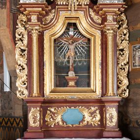 Zdjęcie nr 1: Ołtarz przyścienny, architektoniczny, jednokondygnacyjny, jednoosiowy, ze zwieńczeniem. Mensa w typie sarkofagowym z kamiennym portatylem, dekorowana w dolnej partii srebrnymi liśćmi akantu, a w górnej plakietą w kształcie leżącego prostokąta o zaokrąglonych narożach przenikającego owal; kształt wypełniają odchodzące od centralnego pola złote promienie. Ujmują je plakiety ornamentalne z kształtów nawiązujących do motywu rocaille’a; całość mensy groszkowana. Retabulum na cokole o wysuniętych bokach, ujęte parą kolumn o kapitelach akantowych i trzonach zdobionych żłobkowaniem od frontu, wspierających fragmenty belkowania z silnie wysuniętymi fryzem i gzymsem. Pola cokołu retabulum zdobione motywem wici akantowej ujmującej jasnoniebieski kartusz w kształcie leżącego owalu przenikającego się ze stojącym prostokątem. Oś środkową nastawy wypełnia pole w kształcie stojącego prostokąta o wklęsłych górnych narożach, ujęte profilowaną, częściowo złoconą ramą, z motywem liści laurowych. W środku wizerunek ukrzyżowanego Jezusa na tle lustra. Na zasuwie obraz św. Teresy od Dzieciątka Jezus. Kondygnację flankują ażurowe uszaki utworzone z bujnej, mięsistej wici z liści akantu. Zwieńczenie tworzy owalne przedstawienie św. Antoniego Padewskiego otoczone srebrnymi obłokami oraz glorią promienistą o promieniach różnej długości. Zwieńczenie flankuje para nagich aniołków posadowionych na srebrzonych chmurach, umieszczonych na fragmentach belkowania retabulum. 
Struktura polichromowana w kolorze brązowym. Partie detalu architektonicznego i ornamentyka złocone i srebrzone. 
