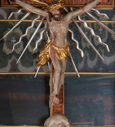 Zdjęcie nr 15: Ołtarz przyścienny, architektoniczny, jednokondygnacyjny, jednoosiowy, ze zwieńczeniem. Mensa w typie sarkofagowym z kamiennym portatylem, dekorowana w dolnej partii srebrnymi liśćmi akantu, a w górnej plakietą w kształcie leżącego prostokąta o zaokrąglonych narożach przenikającego owal; kształt wypełniają odchodzące od centralnego pola złote promienie. Ujmują je plakiety ornamentalne z kształtów nawiązujących do motywu rocaille’a; całość mensy groszkowana. Retabulum na cokole o wysuniętych bokach, ujęte parą kolumn o kapitelach akantowych i trzonach zdobionych żłobkowaniem od frontu, wspierających fragmenty belkowania z silnie wysuniętymi fryzem i gzymsem. Pola cokołu retabulum zdobione motywem wici akantowej ujmującej jasnoniebieski kartusz w kształcie leżącego owalu przenikającego się ze stojącym prostokątem. Oś środkową nastawy wypełnia pole w kształcie stojącego prostokąta o wklęsłych górnych narożach, ujęte profilowaną, częściowo złoconą ramą, z motywem liści laurowych. W środku wizerunek ukrzyżowanego Jezusa na tle lustra. Na zasuwie obraz św. Teresy od Dzieciątka Jezus. Kondygnację flankują ażurowe uszaki utworzone z bujnej, mięsistej wici z liści akantu. Zwieńczenie tworzy owalne przedstawienie św. Antoniego Padewskiego otoczone srebrnymi obłokami oraz glorią promienistą o promieniach różnej długości. Zwieńczenie flankuje para nagich aniołków posadowionych na srebrzonych chmurach, umieszczonych na fragmentach belkowania retabulum. 
Struktura polichromowana w kolorze brązowym. Partie detalu architektonicznego i ornamentyka złocone i srebrzone. 
