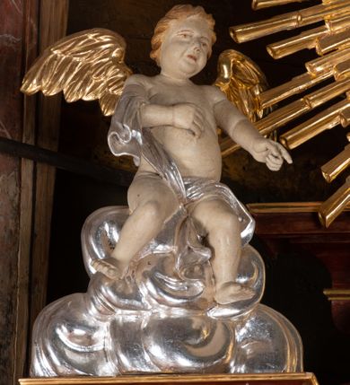 Zdjęcie nr 6: Ołtarz przyścienny, architektoniczny, jednokondygnacyjny, jednoosiowy, ze zwieńczeniem. Mensa w typie sarkofagowym z kamiennym portatylem, dekorowana w dolnej partii srebrnymi liśćmi akantu, a w górnej plakietą w kształcie leżącego prostokąta o zaokrąglonych narożach przenikającego owal; kształt wypełniają odchodzące od centralnego pola złote promienie. Ujmują je plakiety ornamentalne z kształtów nawiązujących do motywu rocaille’a; całość mensy groszkowana. Retabulum na cokole o wysuniętych bokach, ujęte parą kolumn o kapitelach akantowych i trzonach zdobionych żłobkowaniem od frontu, wspierających fragmenty belkowania z silnie wysuniętymi fryzem i gzymsem. Pola cokołu retabulum zdobione motywem wici akantowej ujmującej jasnoniebieski kartusz w kształcie leżącego owalu przenikającego się ze stojącym prostokątem. Oś środkową nastawy wypełnia pole w kształcie stojącego prostokąta o wklęsłych górnych narożach, ujęte profilowaną, częściowo złoconą ramą, z motywem liści laurowych. W środku wizerunek ukrzyżowanego Jezusa na tle lustra. Na zasuwie obraz św. Teresy od Dzieciątka Jezus. Kondygnację flankują ażurowe uszaki utworzone z bujnej, mięsistej wici z liści akantu. Zwieńczenie tworzy owalne przedstawienie św. Antoniego Padewskiego otoczone srebrnymi obłokami oraz glorią promienistą o promieniach różnej długości. Zwieńczenie flankuje para nagich aniołków posadowionych na srebrzonych chmurach, umieszczonych na fragmentach belkowania retabulum. 
Struktura polichromowana w kolorze brązowym. Partie detalu architektonicznego i ornamentyka złocone i srebrzone. 
