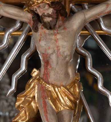 Zdjęcie nr 4: Ołtarz przyścienny, architektoniczny, jednokondygnacyjny, jednoosiowy, ze zwieńczeniem. Mensa w typie sarkofagowym z kamiennym portatylem, dekorowana w dolnej partii srebrnymi liśćmi akantu, a w górnej plakietą w kształcie leżącego prostokąta o zaokrąglonych narożach przenikającego owal; kształt wypełniają odchodzące od centralnego pola złote promienie. Ujmują je plakiety ornamentalne z kształtów nawiązujących do motywu rocaille’a; całość mensy groszkowana. Retabulum na cokole o wysuniętych bokach, ujęte parą kolumn o kapitelach akantowych i trzonach zdobionych żłobkowaniem od frontu, wspierających fragmenty belkowania z silnie wysuniętymi fryzem i gzymsem. Pola cokołu retabulum zdobione motywem wici akantowej ujmującej jasnoniebieski kartusz w kształcie leżącego owalu przenikającego się ze stojącym prostokątem. Oś środkową nastawy wypełnia pole w kształcie stojącego prostokąta o wklęsłych górnych narożach, ujęte profilowaną, częściowo złoconą ramą, z motywem liści laurowych. W środku wizerunek ukrzyżowanego Jezusa na tle lustra. Na zasuwie obraz św. Teresy od Dzieciątka Jezus. Kondygnację flankują ażurowe uszaki utworzone z bujnej, mięsistej wici z liści akantu. Zwieńczenie tworzy owalne przedstawienie św. Antoniego Padewskiego otoczone srebrnymi obłokami oraz glorią promienistą o promieniach różnej długości. Zwieńczenie flankuje para nagich aniołków posadowionych na srebrzonych chmurach, umieszczonych na fragmentach belkowania retabulum. 
Struktura polichromowana w kolorze brązowym. Partie detalu architektonicznego i ornamentyka złocone i srebrzone. 
