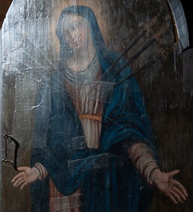 Zdjęcie nr 1: Obraz w kształcie stojącego prostokąta zamkniętego od góry łukiem półkolistym. W centrum kompozycji ukazana stojąca frontalnie Maria ukazana w typie Matki Boskiej Bolesnej. Twarz zwrócona w trzech czwartych w prawo, ręce opuszczone wzdłuż tułowia z dłońmi rozchylonymi na boki. W pierś postaci wbite siedem mieczy o ozdobnych rękojeściach. Maria przedstawiona jako młoda kobieta o owalnej twarzy z dużymi, ciemnymi oczami i długim prostym nosem. Karnacja jasna, policzki delikatnie zaróżowione. Postać ubrana jest w jasnoróżową suknię z długimi rękawami przewiązaną w talii złotym pasem oraz zarzucony na głowę i ramiona ciemnoniebieski płaszcz. Pod szyją oraz na głowie biała chusta. Wokół głowy Marii widoczny świetlisty nimb. Tło obrazu jednolite, ciemnobrązowe. Kolorystyka ciemna, ciepła.
