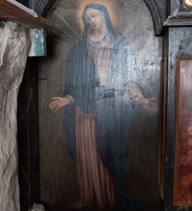 Zdjęcie nr 3: Obraz w kształcie stojącego prostokąta zamkniętego od góry łukiem półkolistym. W centrum kompozycji ukazana stojąca frontalnie Maria ukazana w typie Matki Boskiej Bolesnej. Twarz zwrócona w trzech czwartych w prawo, ręce opuszczone wzdłuż tułowia z dłońmi rozchylonymi na boki. W pierś postaci wbite siedem mieczy o ozdobnych rękojeściach. Maria przedstawiona jako młoda kobieta o owalnej twarzy z dużymi, ciemnymi oczami i długim prostym nosem. Karnacja jasna, policzki delikatnie zaróżowione. Postać ubrana jest w jasnoróżową suknię z długimi rękawami przewiązaną w talii złotym pasem oraz zarzucony na głowę i ramiona ciemnoniebieski płaszcz. Pod szyją oraz na głowie biała chusta. Wokół głowy Marii widoczny świetlisty nimb. Tło obrazu jednolite, ciemnobrązowe. Kolorystyka ciemna, ciepła.