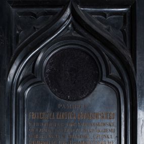 Zdjęcie nr 1: Epitafium w formie stojącego prostokąta,  ujęte szerokim obramieniem, z głęboką płyciną z motywem oślego łuku z wpisanym w niego maswerkiem oraz z maswerkami w nadłuczach. Nad górną krawędzią ujęty dwiema ulistnionymi wolutkami krzyżyk łaciński o fazowanych krawędziach. W łuku okrągła płycina z polem na portret, poniżej inskrypcja „PAMIĘCI / FRANCISZKA KANDYDA NOWAKOWSKIEGO / D(OKTO)RA FIL(OZOFII) CZŁONKA B(IERNEGO) TOW(ARZYSTWA) NAUK(OWEGO) KRAKOWSKIE/GO CZŁONKA NADZWYCZAJNEGO AKADEMII / UMIEJĘTNOŚCI W KRAKOWIE_CZŁONKA / HONOROWEGO TOW(ARZYSTWA) PEDAGOGICZNEGO WE / LWOWIE I WIELU INNYCH TOW(ARZYSTW) NAUK(OWYCH) I HUMA/NITARNYCH. WIELOLETNEGO ZASTĘPCY PREZE/SA RADY SZKOLNEJ OKRĘGU WADOWICKIEGO ZA/SŁUŻONEGO AUTORA NA POLU PEDAGOGII, I GOR/LIWEGO MIŁOŚNIKA OJCZYSTEJ MOWY. / „CHODZIŁ W OCZACH TWOICH PANIE W PRAWDZIE I SPRAWIEDLIWOŚCI / PRAWEM SERCEM BYŁ Z TOBĄ, A TY ZACHOWAŁEŚ MU MIŁOSIERDZIE TWOJE". / Z KS(IĘGI) III KRÓL(EWSKIEJ) ROZ(DZIAŁ) 3. / *3 X 1813 W POZNANIU † 19 XI 1881 W SUCHY. / NAJZACNIEJSZEMU MĘŻOWI ŻONA / PROSI POBOŻNYCH  O MODLITWĘ.”
