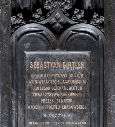 Zdjęcie nr 1: Epitafium w kształcie stojącego prostokąta, z niszą ujętą laskowaniem przechodzącym w podwójny, profilowany łuk, nad którym łuk kotarowy z krzyżującymi się laskowaniami, ozdobiony kwiatonami i zwieńczony krzyżem; nad łukiem rząd ślepych maswerków. Część środkowa z prostokątną tablicą z inskrypcją „SEBASTYAN GIRTLER / FILOZOFII I MEDYCYNY DOKTOR / W UNIWERSYTECIE JAGIELLOŃSKIM / PROFESSOR, DZIEKAN_REKTOR / TOWARZYSTWA NAUKOWEGO / PREZES_SENATOR / RZECZYPOSPOLITEJ KRAKOWSKIEJ / *1767 +1833 / KU PAMIĘCI WIELOLETNICH USŁUG W ZAWO/DZIE URZĘDOWANIA I NAUCZYCIELSTWA / PUBLICZNEGO POŁOŻONYCH, POMNIK TEN / W ŻALU POGRĄŻONE DZIECI NAJLEPSZEMU / POŚWIĘCAJĄ OJCU”. W prawym dolnym rogu sygnatura „E(dward) Stehlik.”