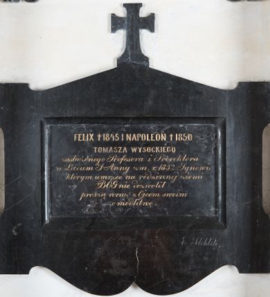 Zdjęcie nr 1: Epitafium w kształcie leżącego prostokąta, z szeroką ramą z uszakami, z dolną krawędzią wykrojoną faliście i górną, trójkątną zwieńczoną krzyżem. W polu inskrypcja „FELIX † 1845 I NAPOLEON † 1850 / TOMASZA WYSOCKIEGO / zasłużonego Profesora i Prorektora / w Liceum S(więtej) Anny zm(arłego) r(oku) 1833 Synowie, / którym umrzeć na rodzinnej ziemi / BÓG nie dozwolił / proszą wraz z Ojcem swoim / o modlitwę”. W prawym dolnym rogu sygnatura „E(dward) Stehlik”. 